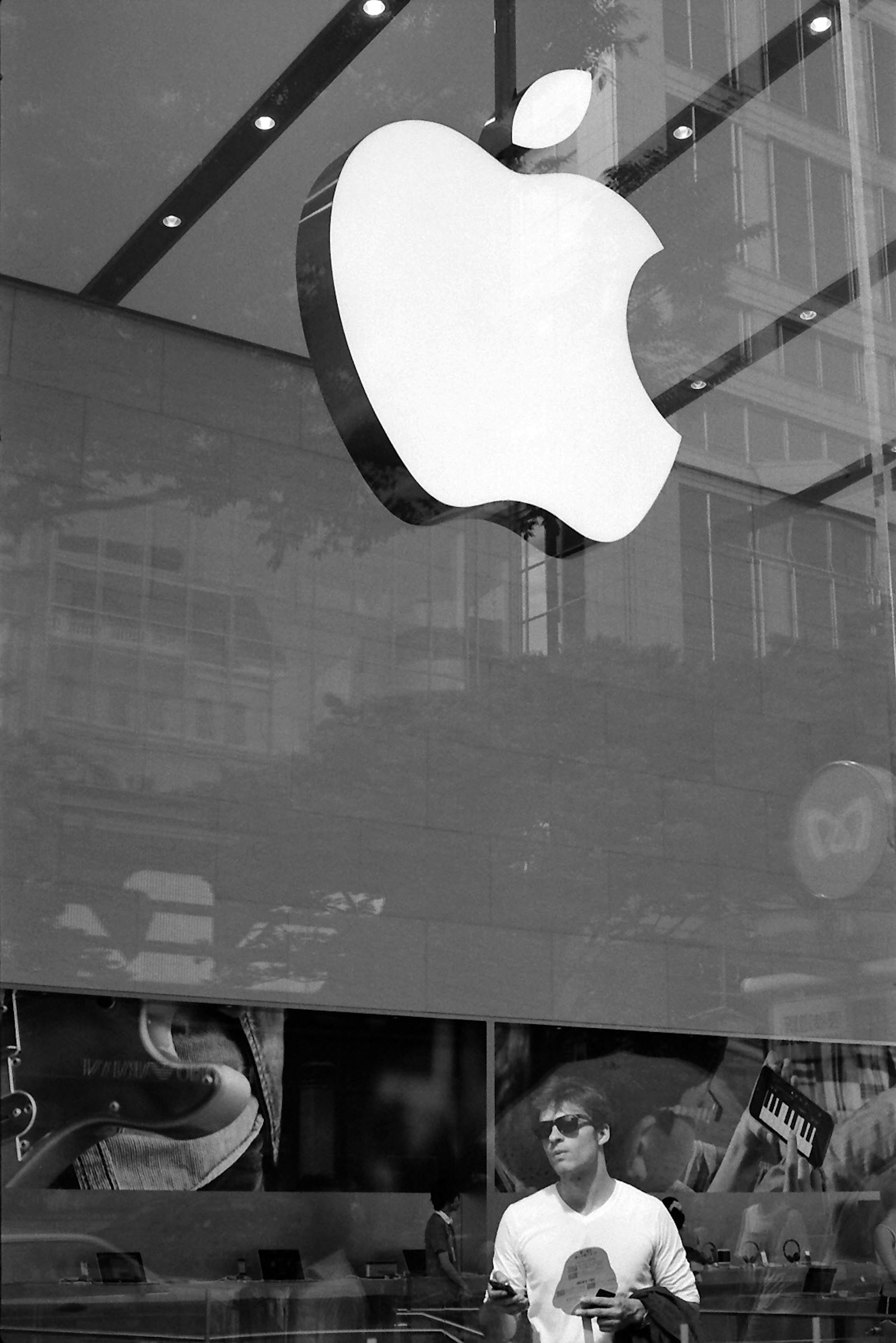 Pria berdiri di depan logo Apple di toko