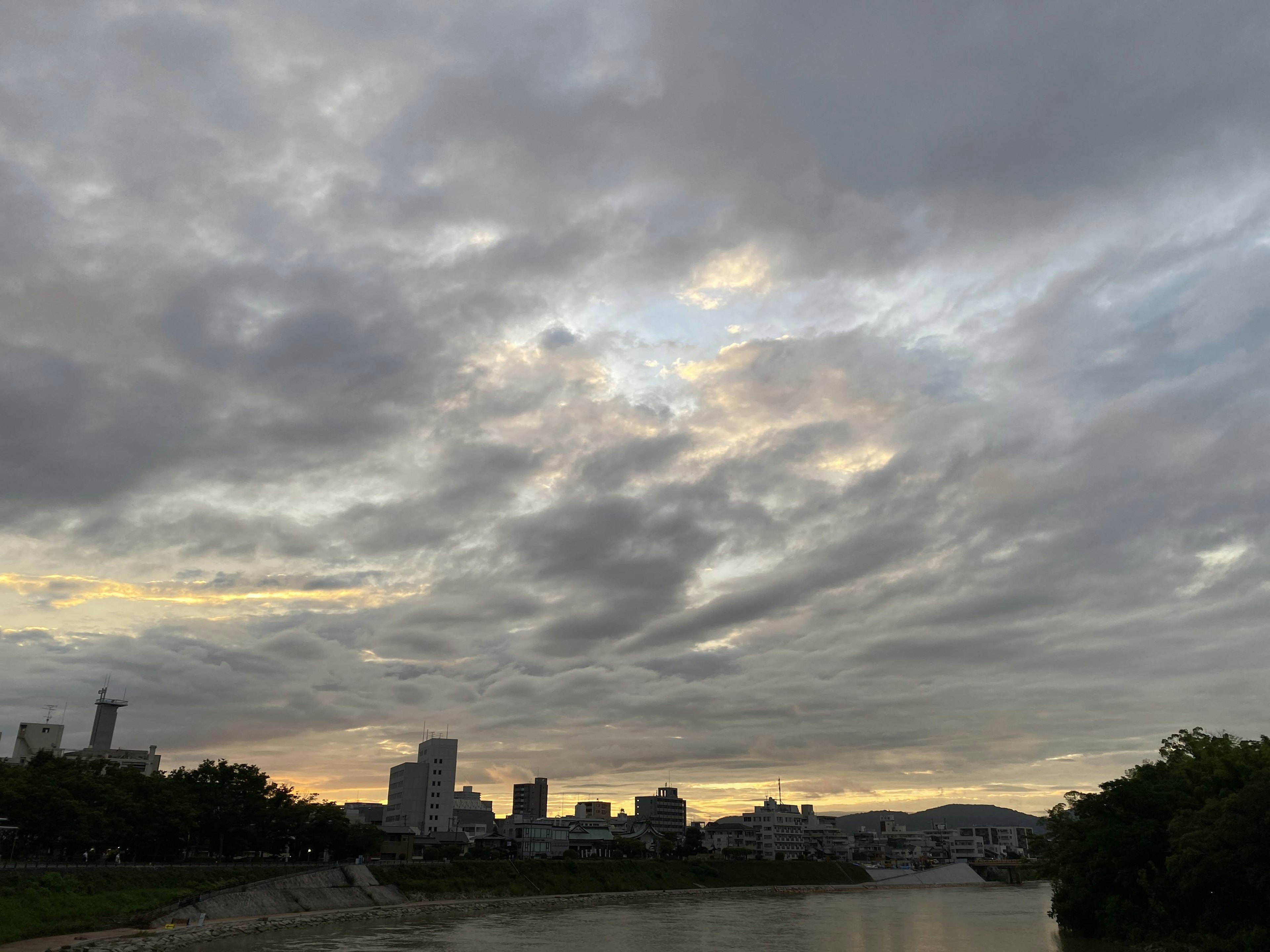 Una vista panoramica di un cielo nuvoloso sopra un fiume con lo skyline di una città sullo sfondo