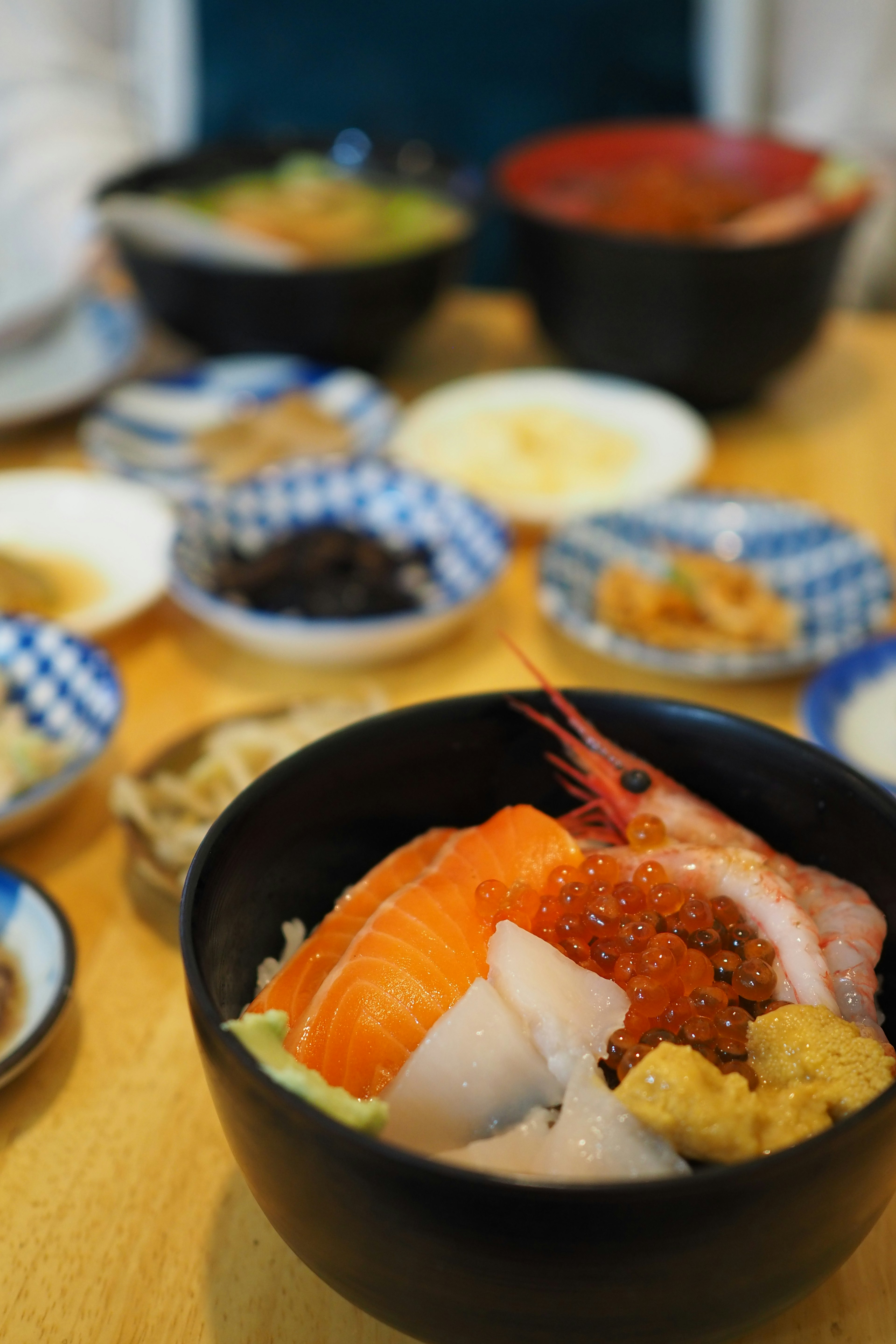 A colorful seafood bowl with various small dishes on a table