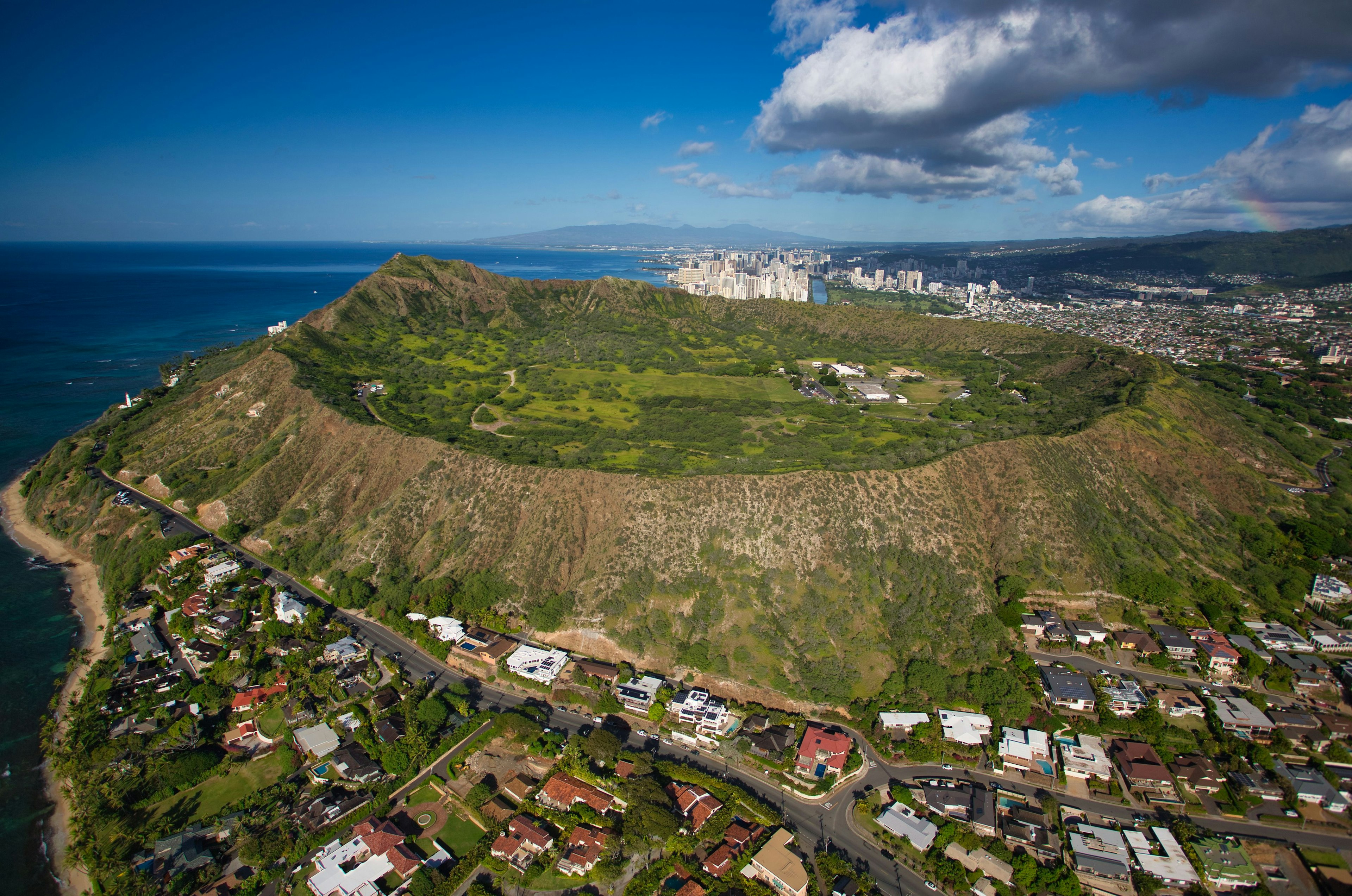 มุมมองทางอากาศของ Diamond Head มีเนินเขาสีเขียวและมหาสมุทรสีน้ำเงิน