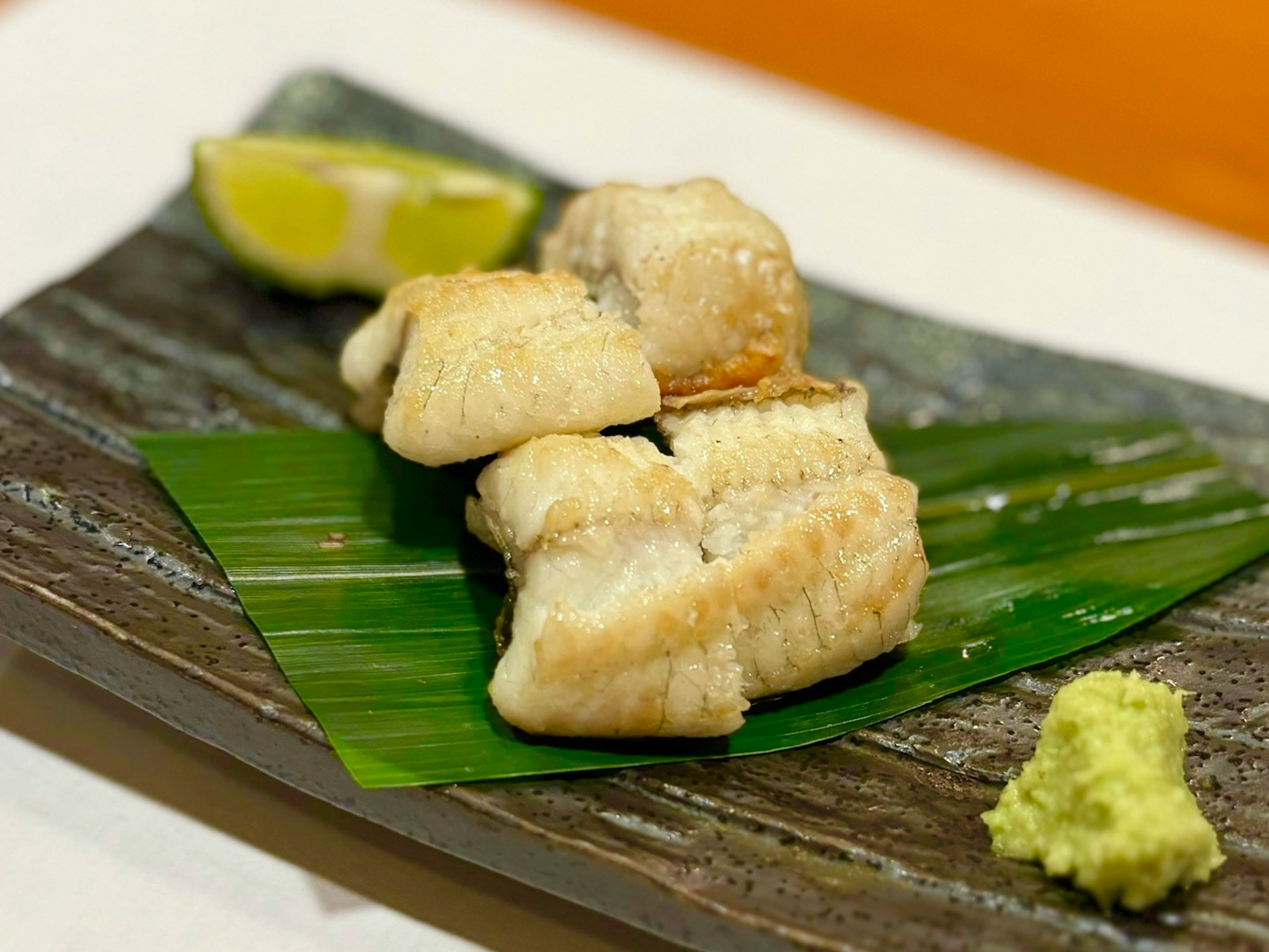 Poisson grillé sur une assiette avec du wasabi et du citron vert