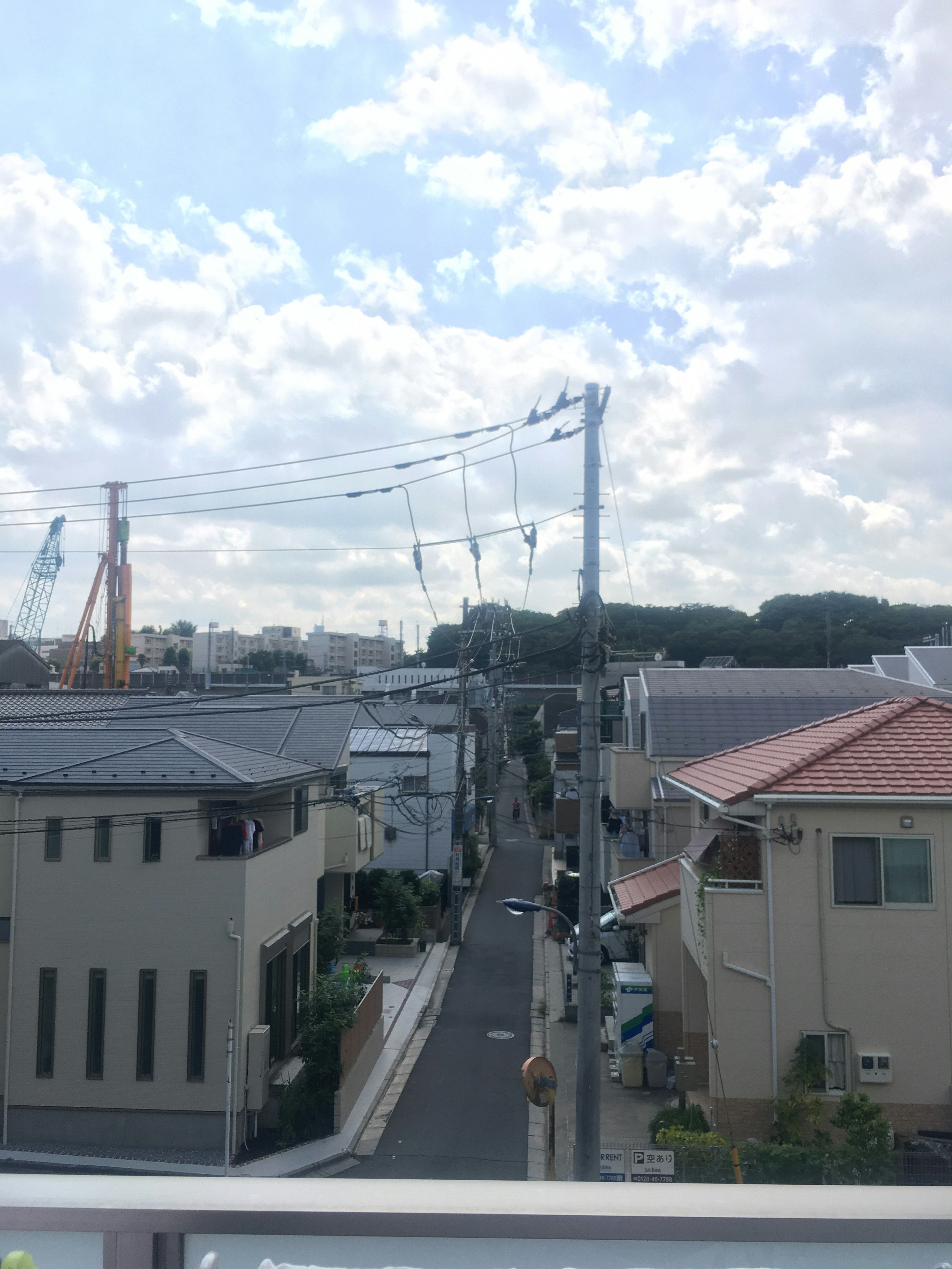 Scena di una strada residenziale con cielo blu chiaro e pali elettrici