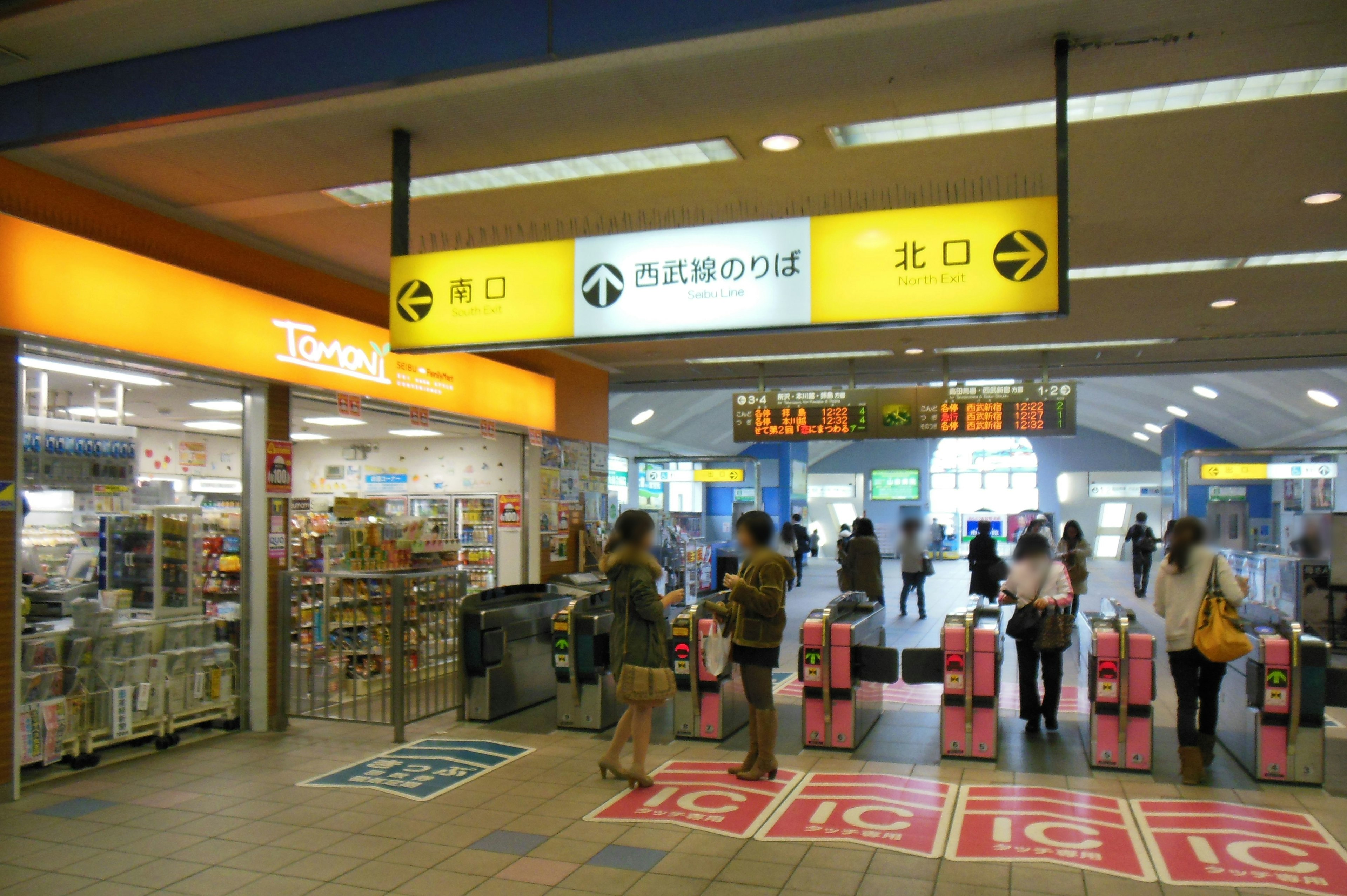 View of a train station entrance with ticket gates and shops bustling with people