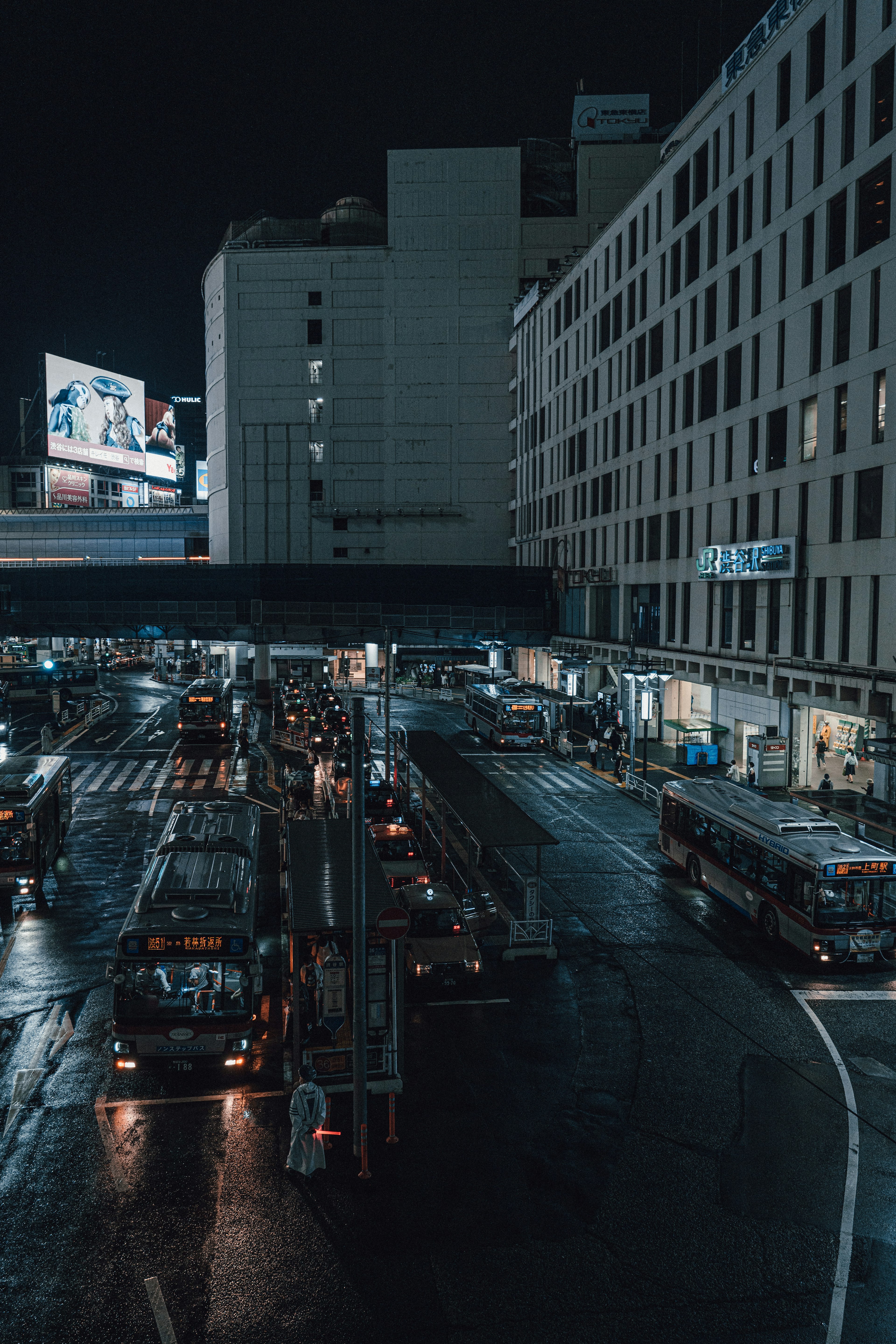 Nighttime urban scene featuring buses and vehicles at an intersection