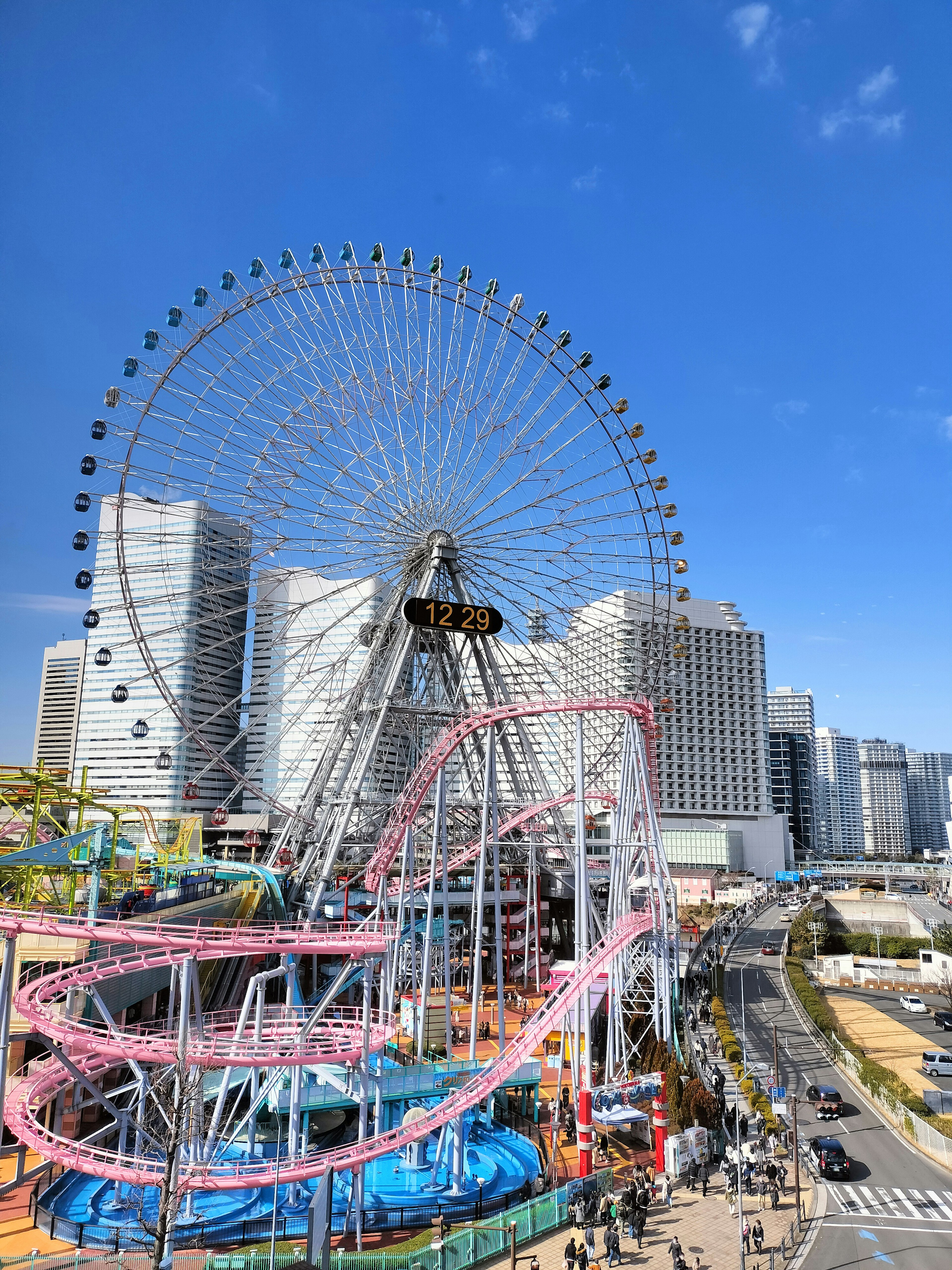 Vista di una ruota panoramica e giostre sotto un cielo blu