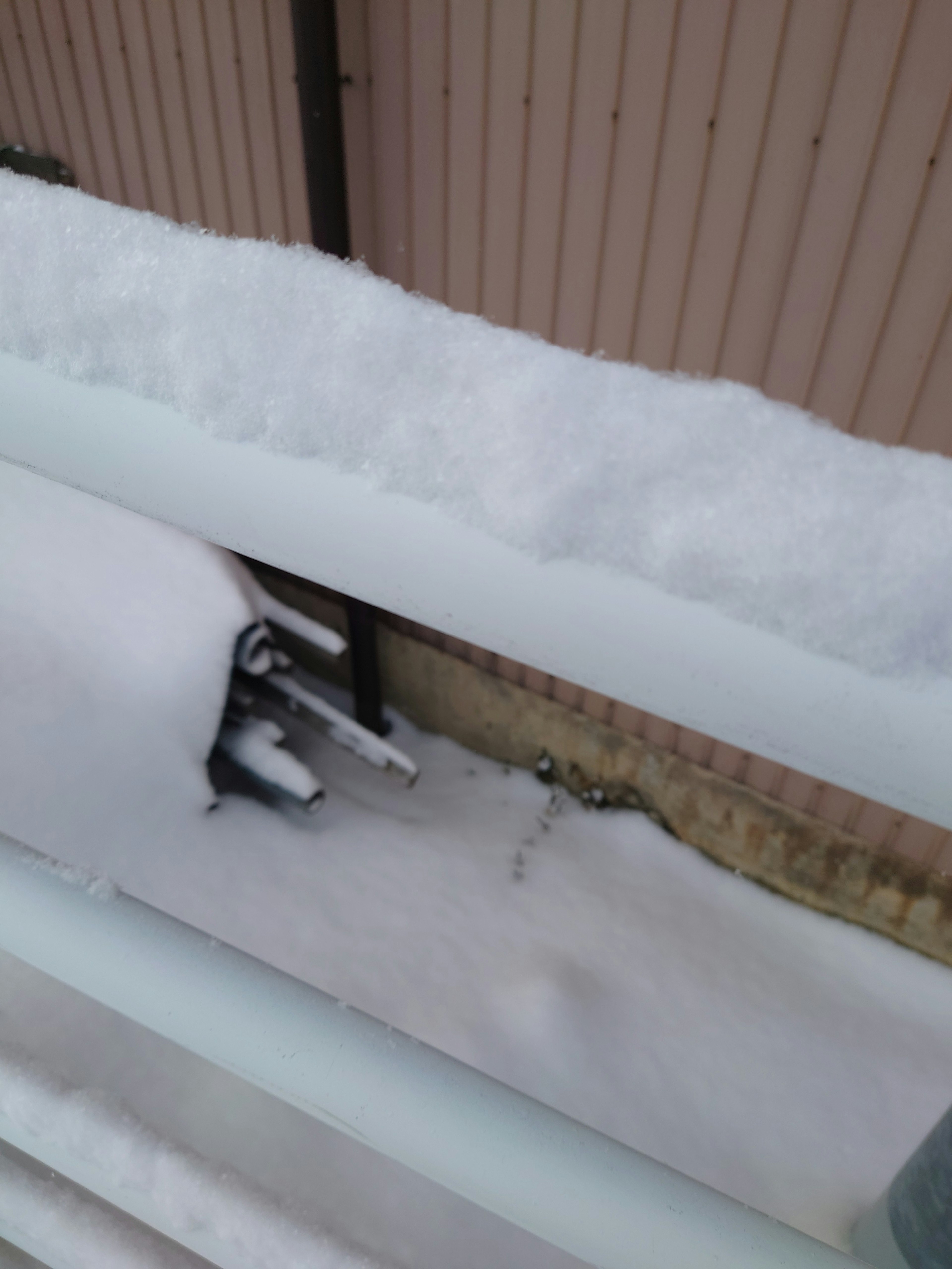 Snow-covered balcony railing with a hidden object below