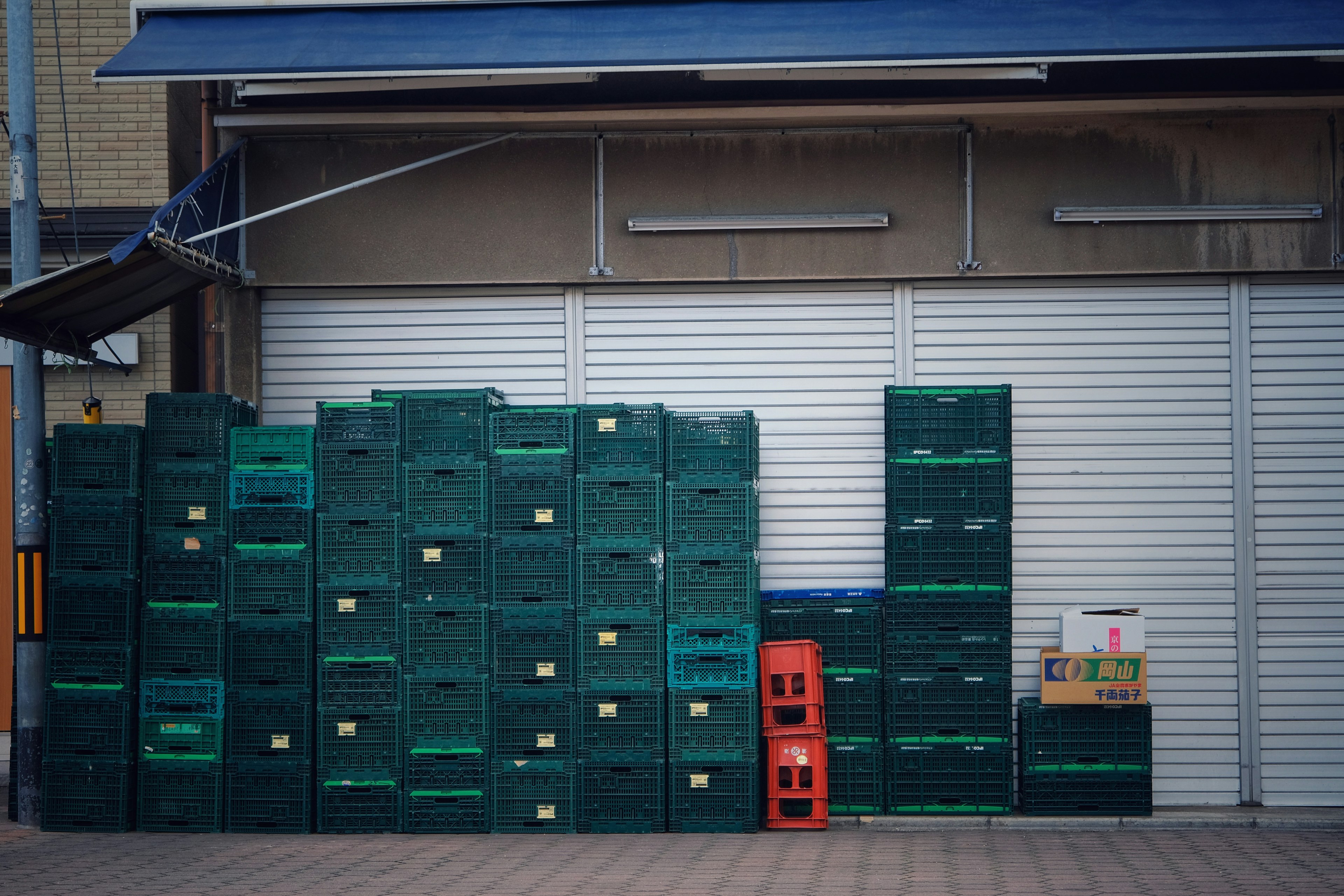 Cajas de plástico verde apiladas frente a una tienda