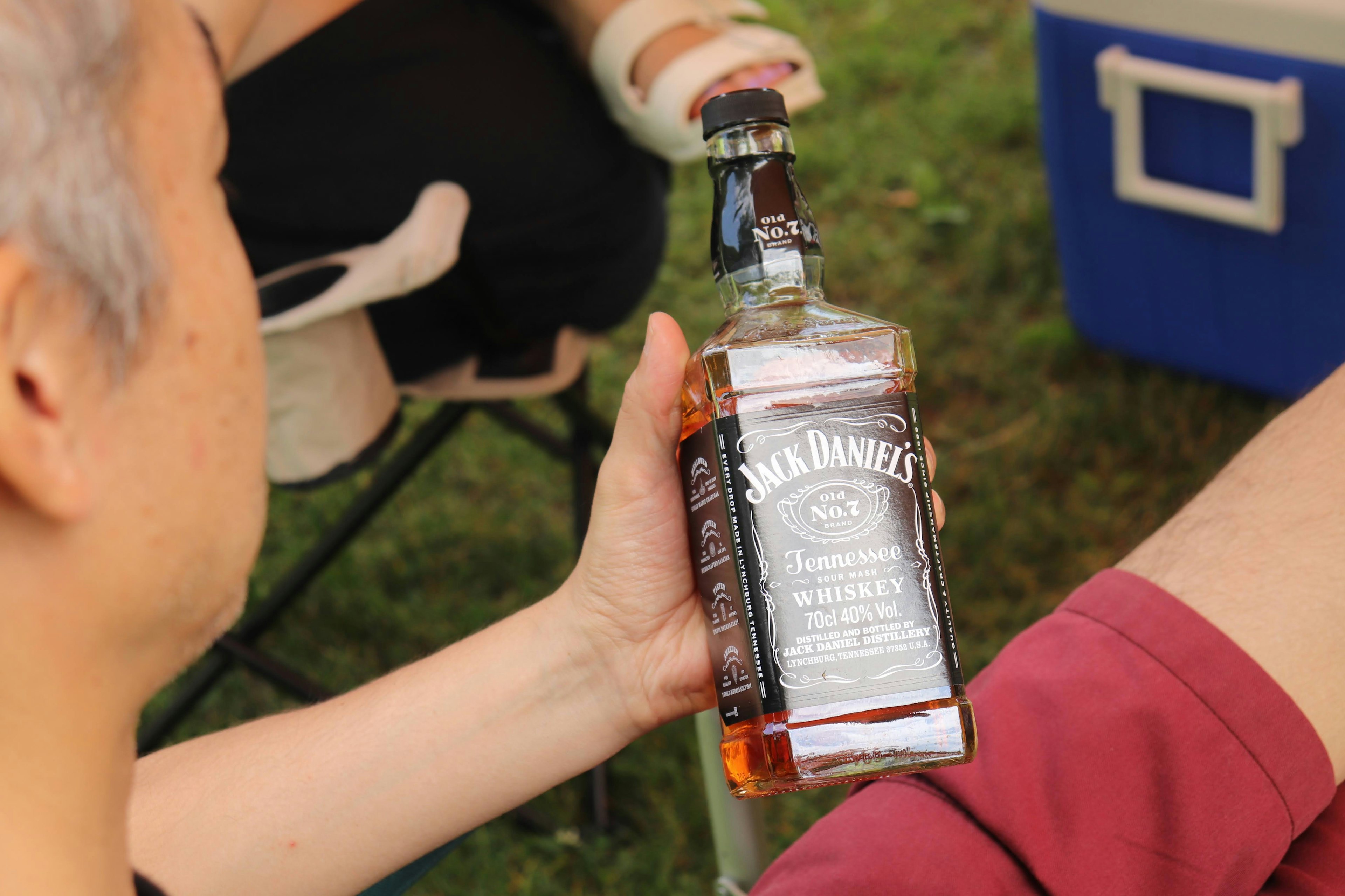 Person, die eine Flasche Jack Daniel's Whiskey im Freien hält