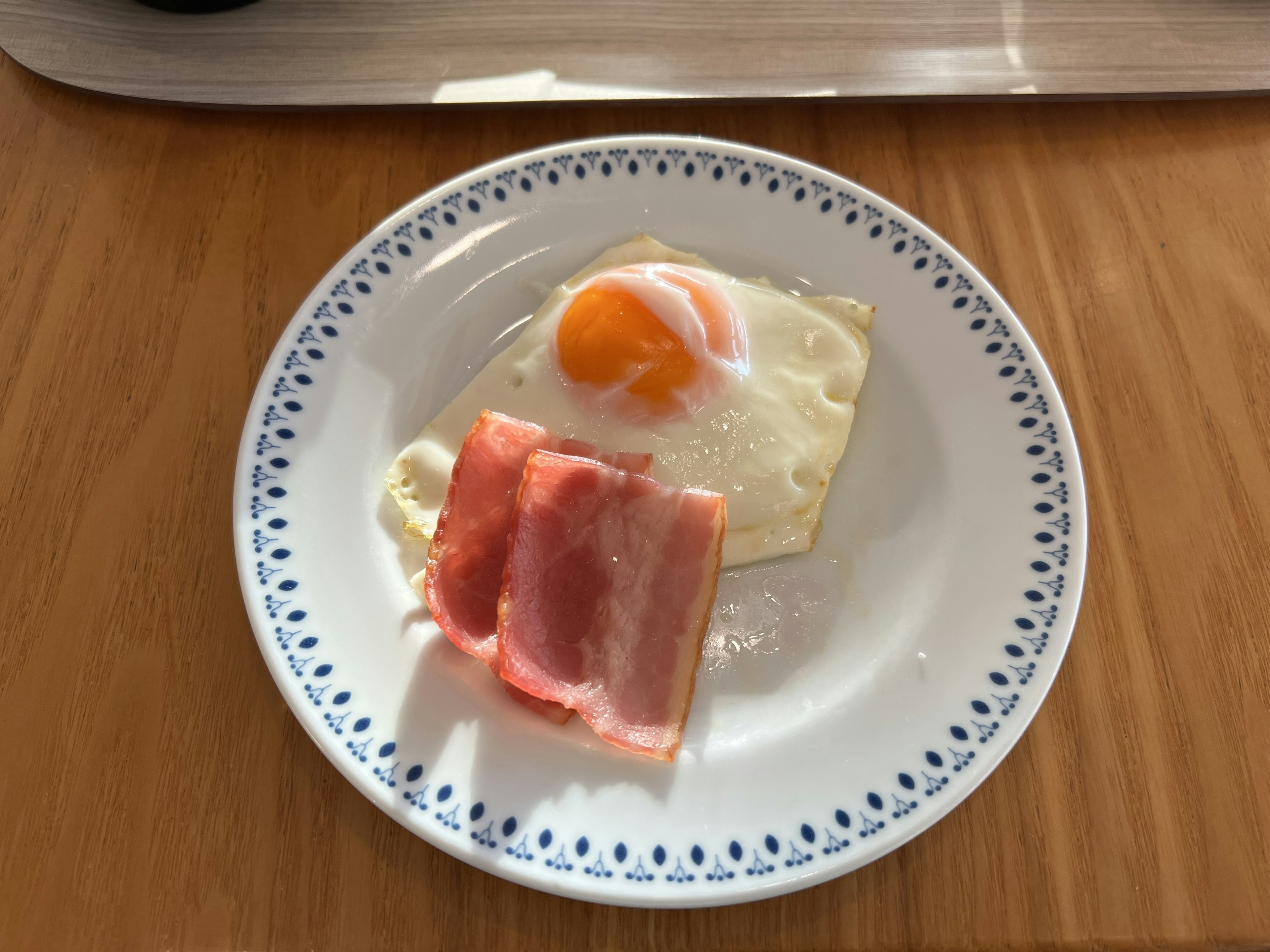 Huevo frito con tocino en un plato blanco