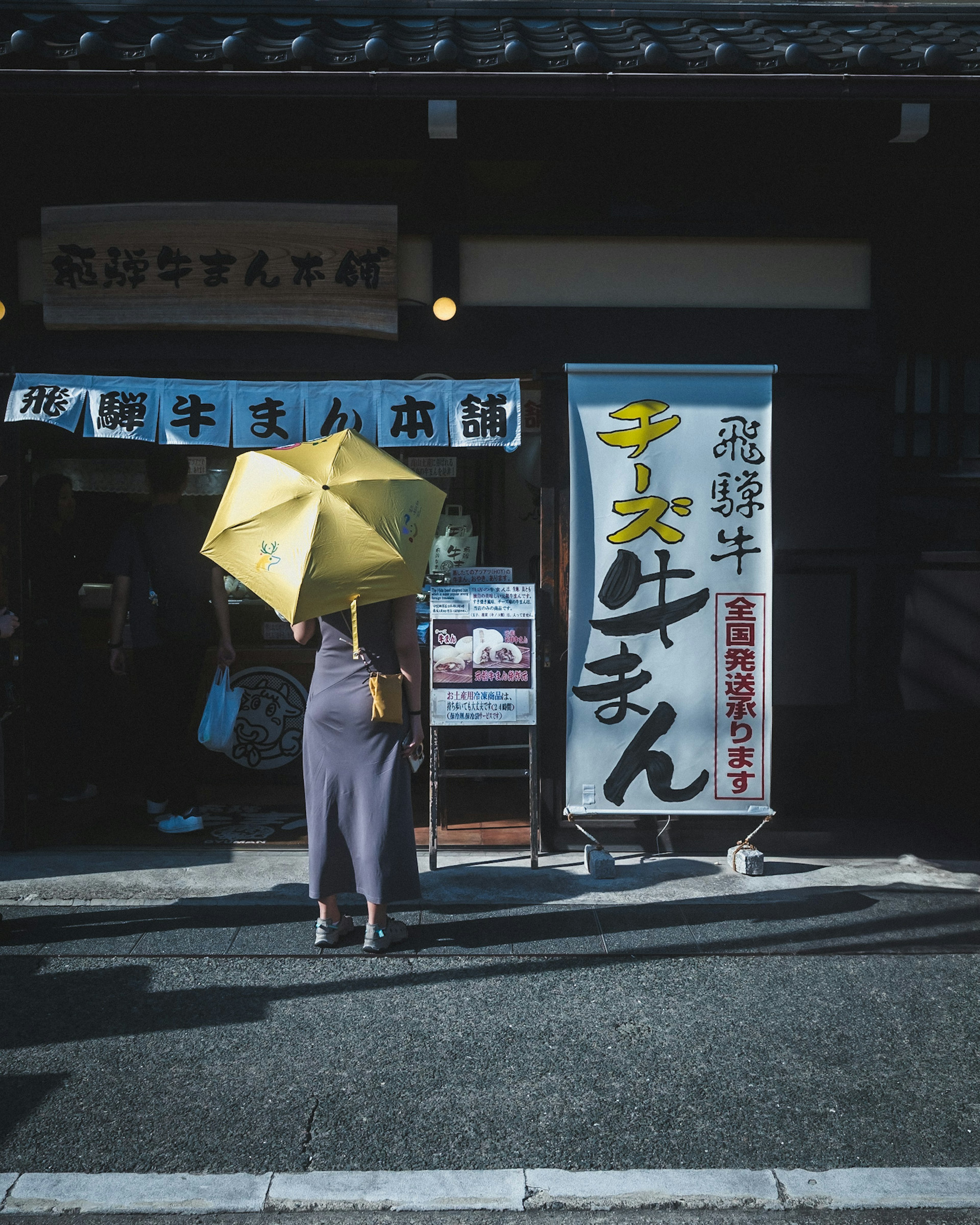 拿著黃色雨傘的女人站在商店前面