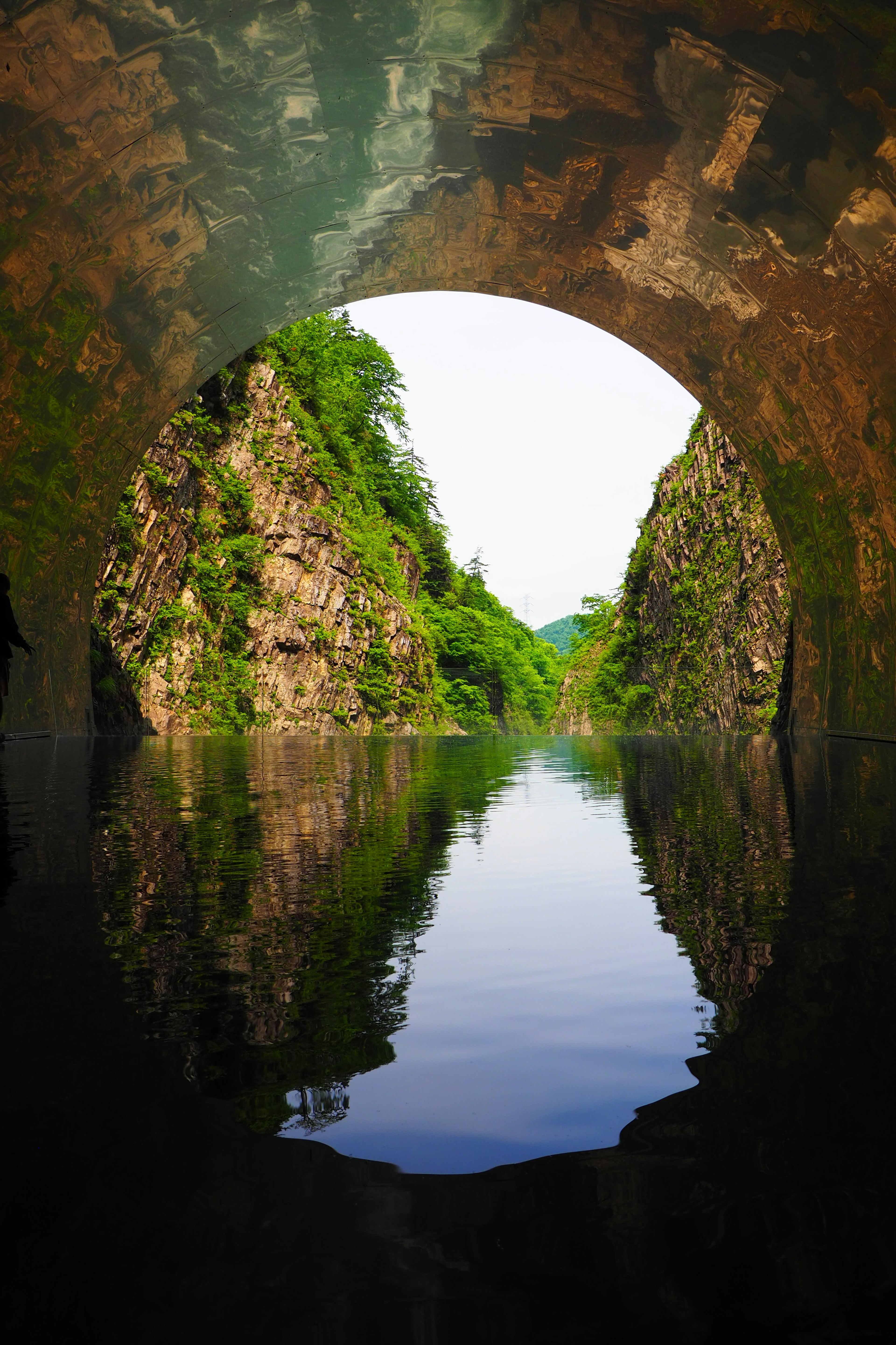 Vue de l'eau réfléchissant la verdure entre des falaises rocheuses à travers un tunnel