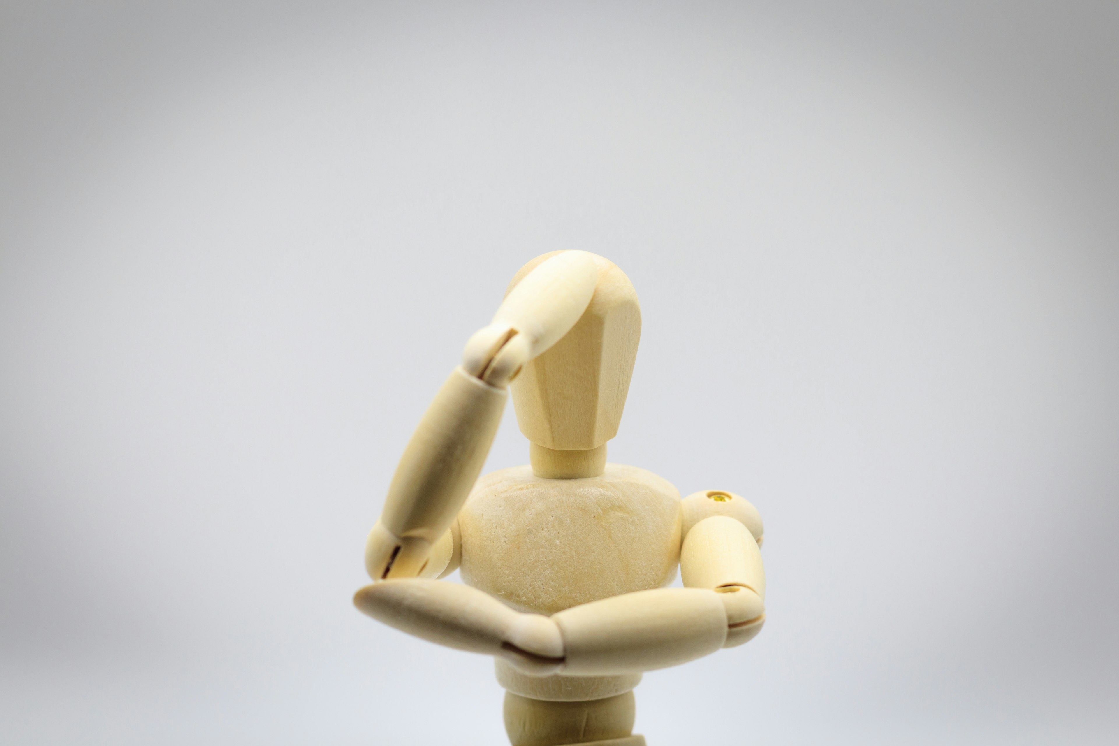 Wooden mannequin in a thinking pose