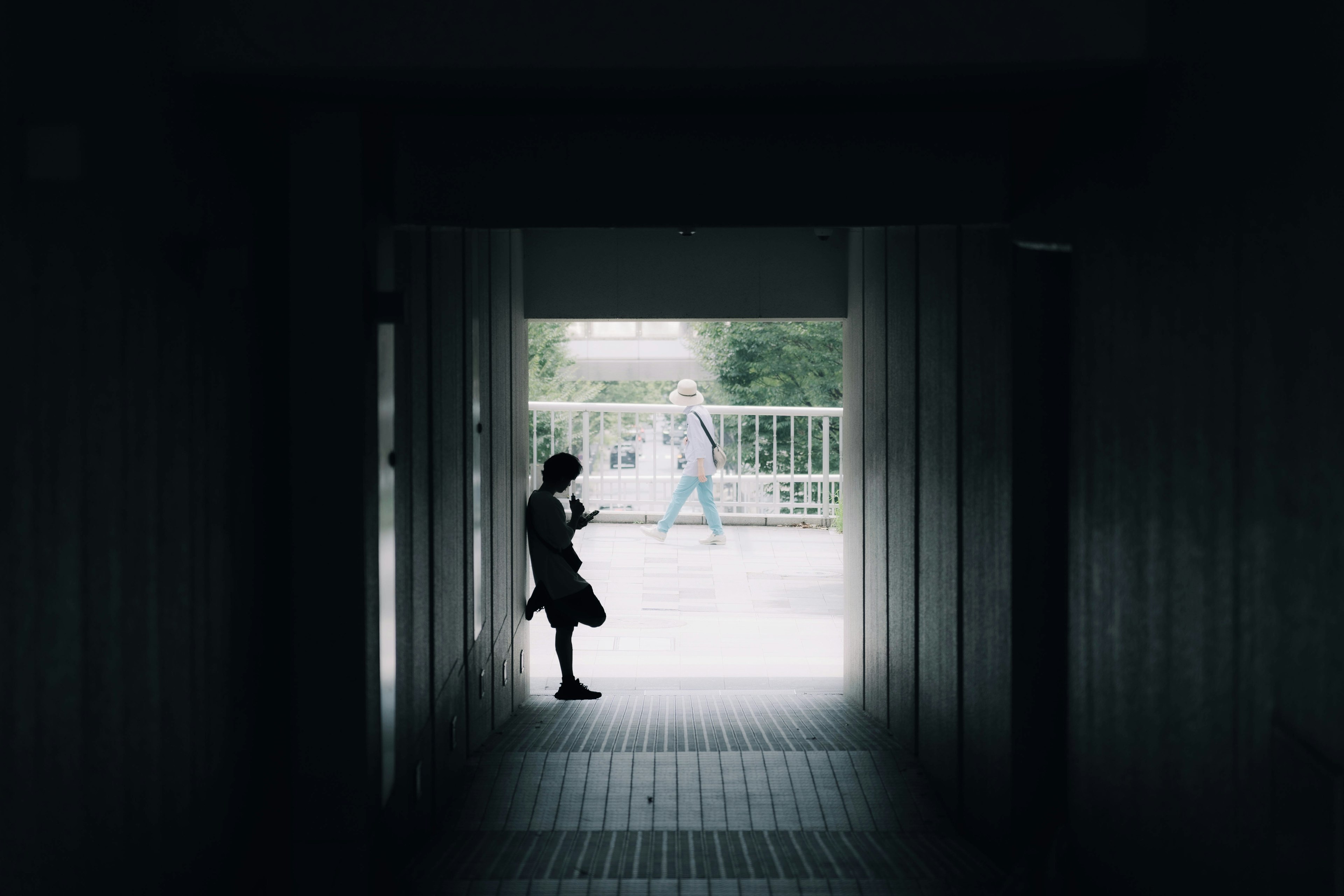 暗い通路の中で立っている人影と背景の明るい風景