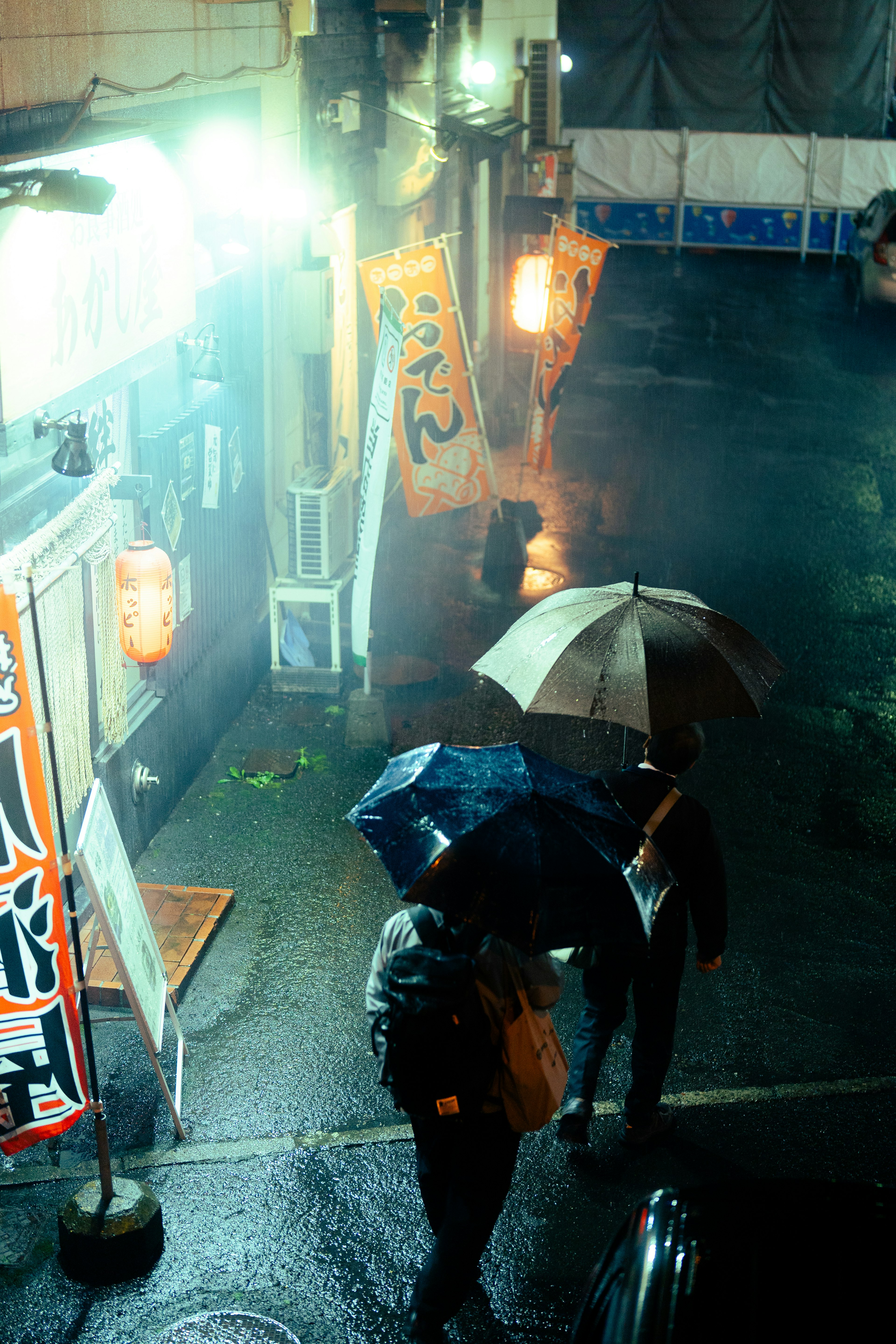 Personnes avec des parapluies sous la pluie près de panneaux lumineux