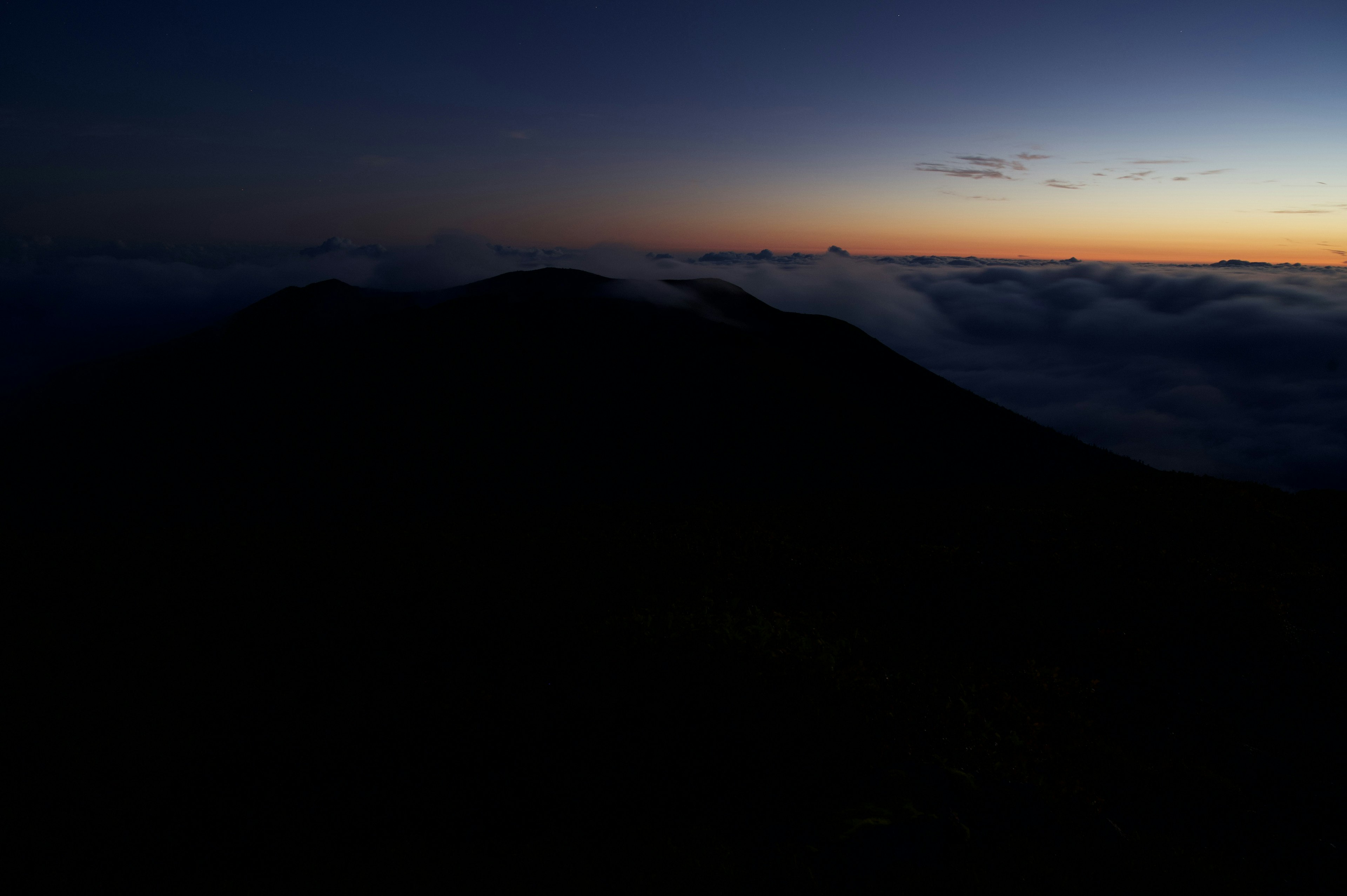 Silhouette di una montagna contro un cielo dell'alba sopra le nuvole