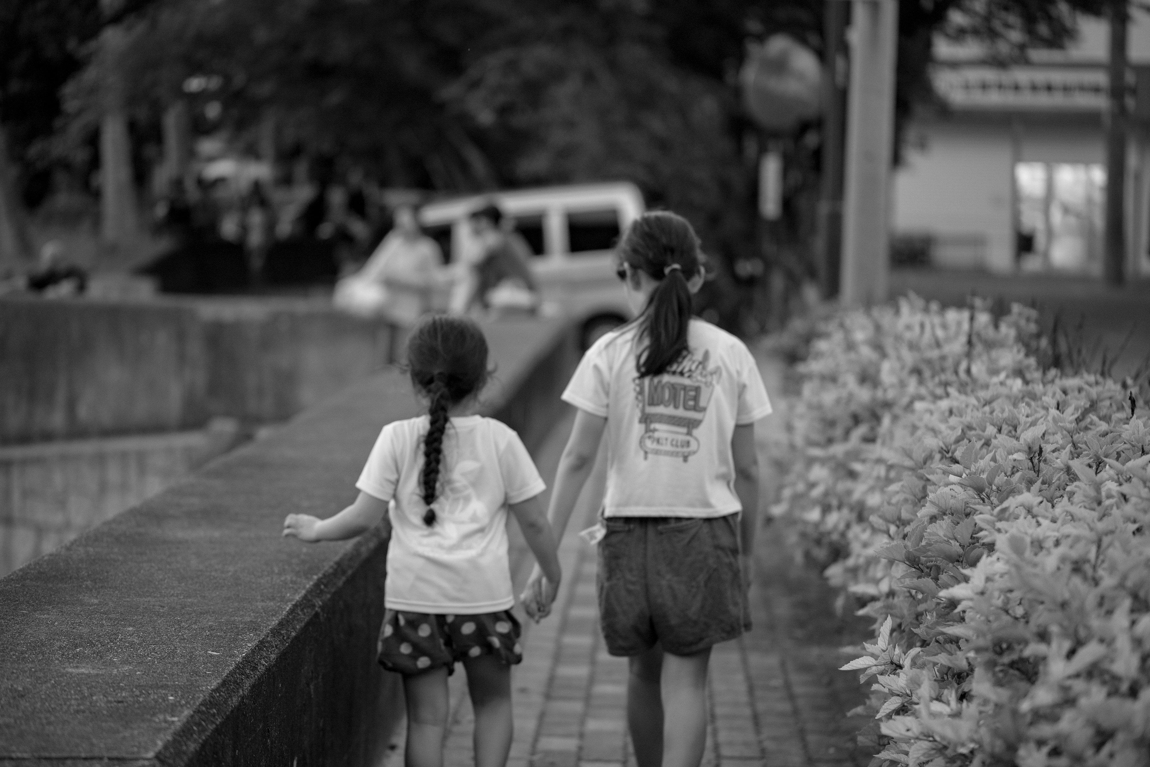 Due bambini che camminano mano nella mano su un sentiero in bianco e nero