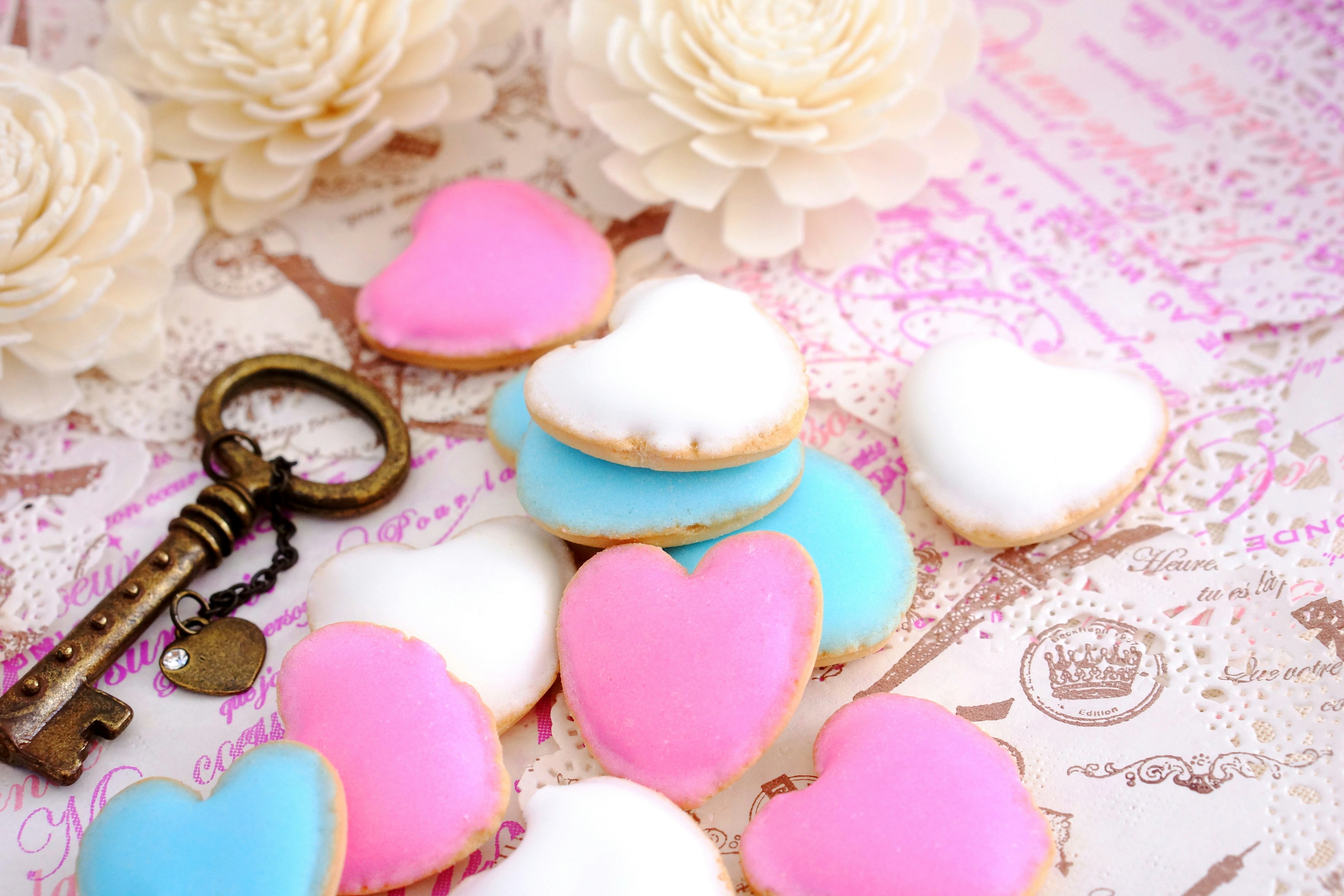 Des biscuits en forme de cœur colorés avec une clé vintage et des décorations florales en arrière-plan