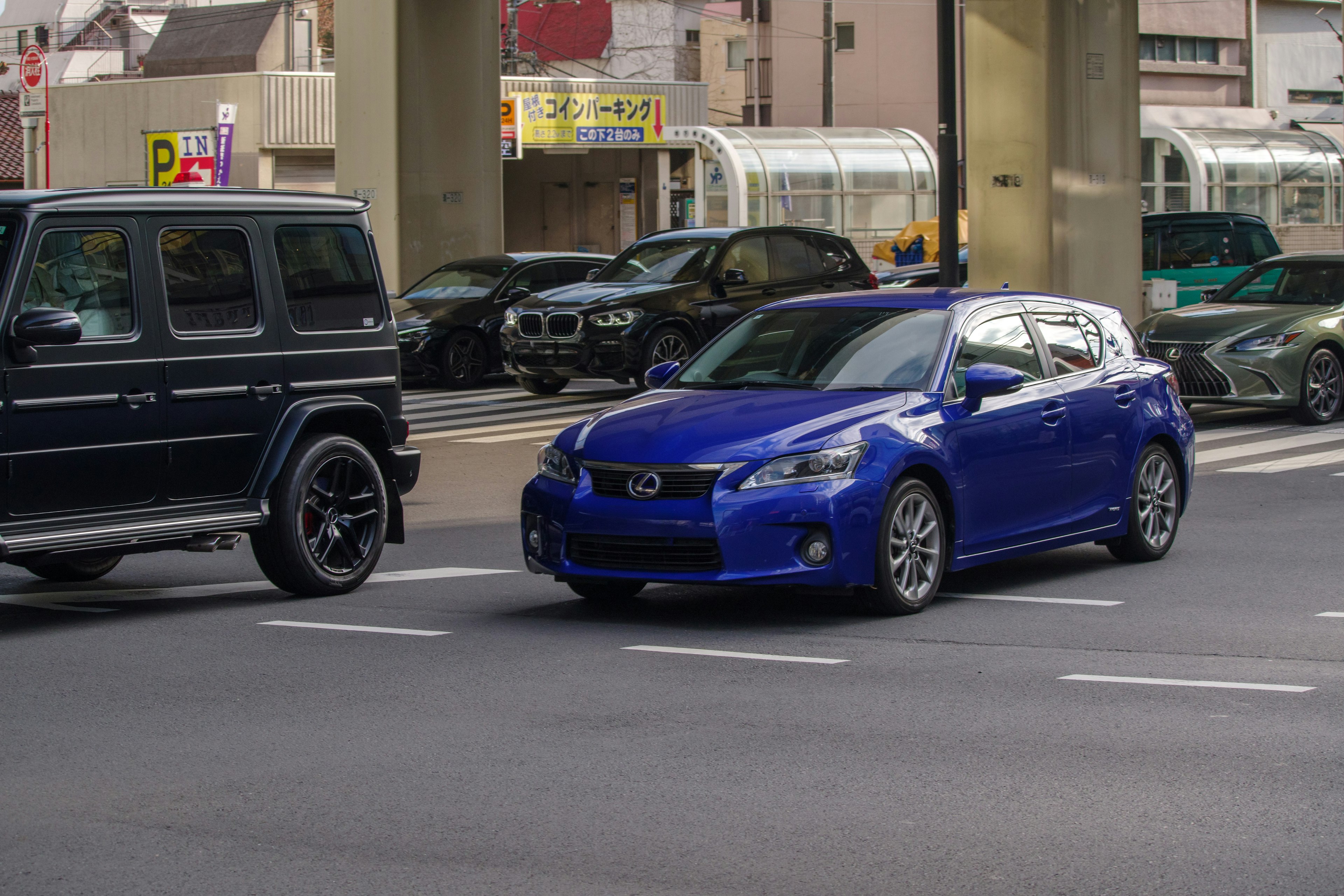 Une voiture bleue et un SUV noir passant à un carrefour