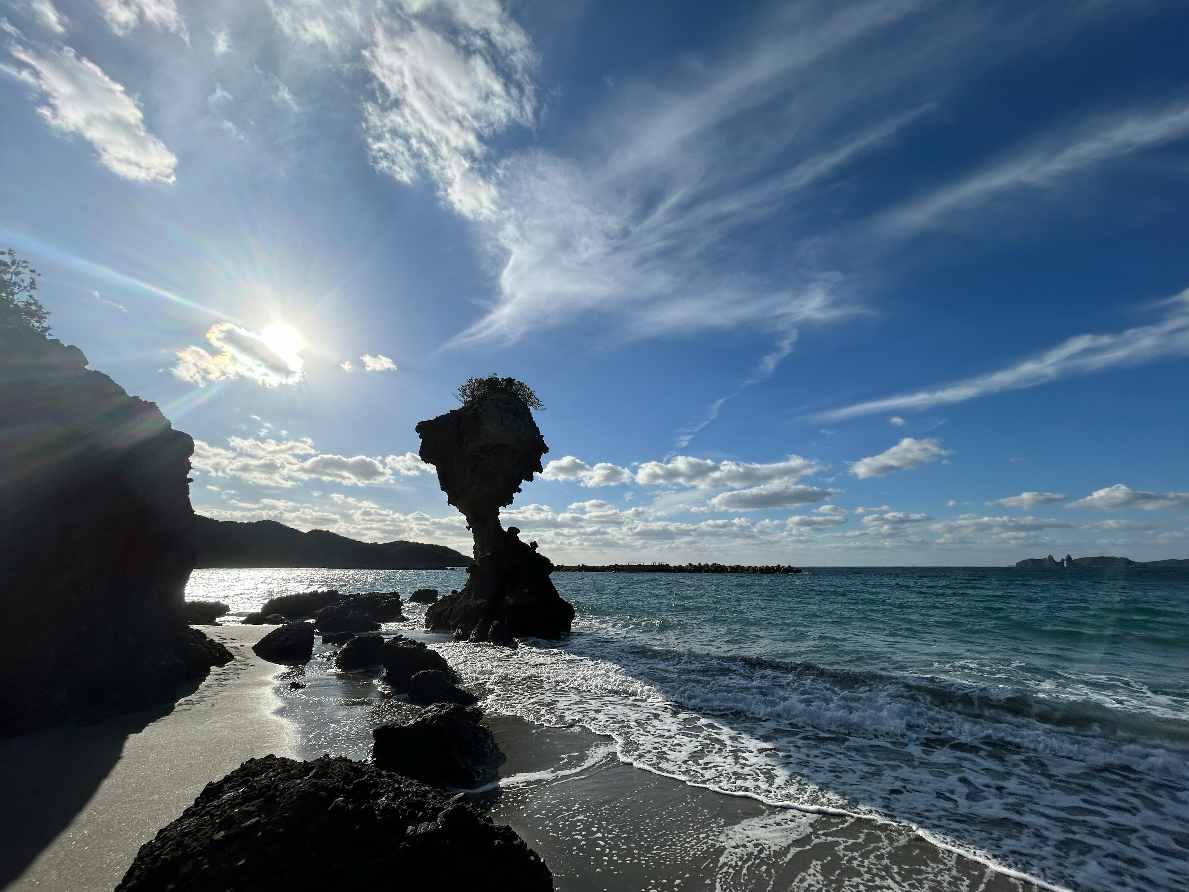 Formation rocheuse unique se tenant sur la plage avec des vagues et de la lumière du soleil