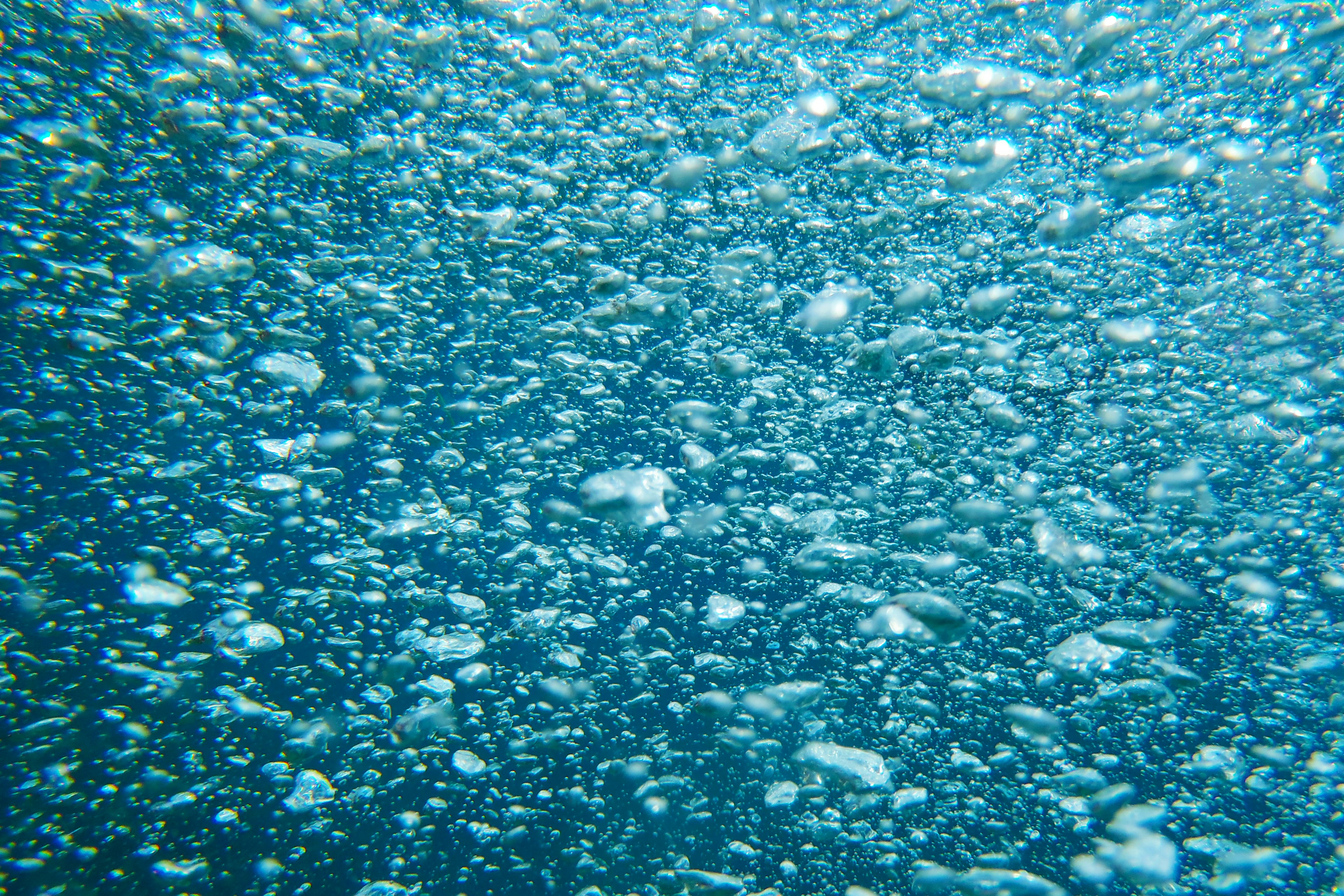 Acercamiento de burbujas bajo el agua con fondo azul