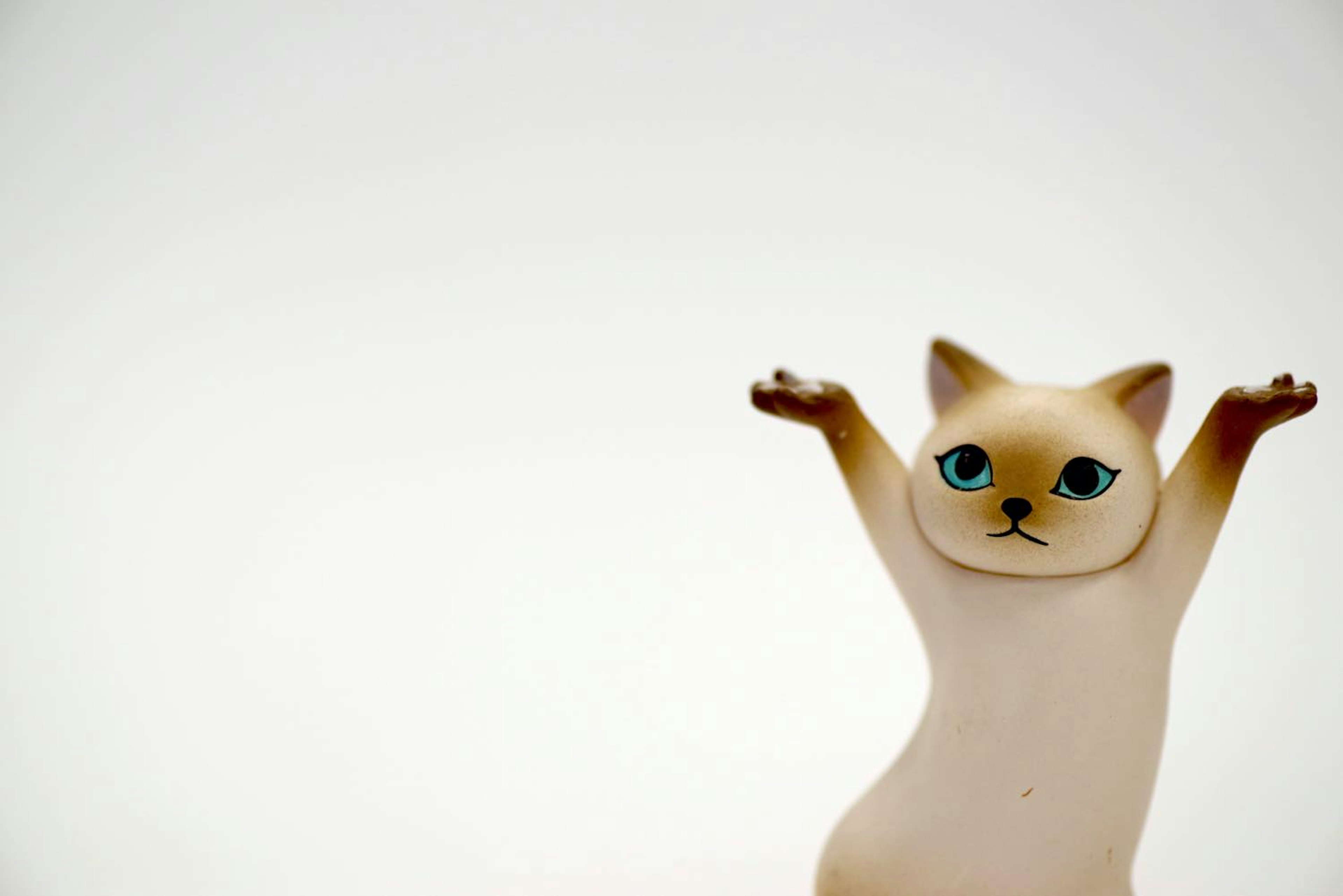 A figurine of a cat with blue eyes raising its arms