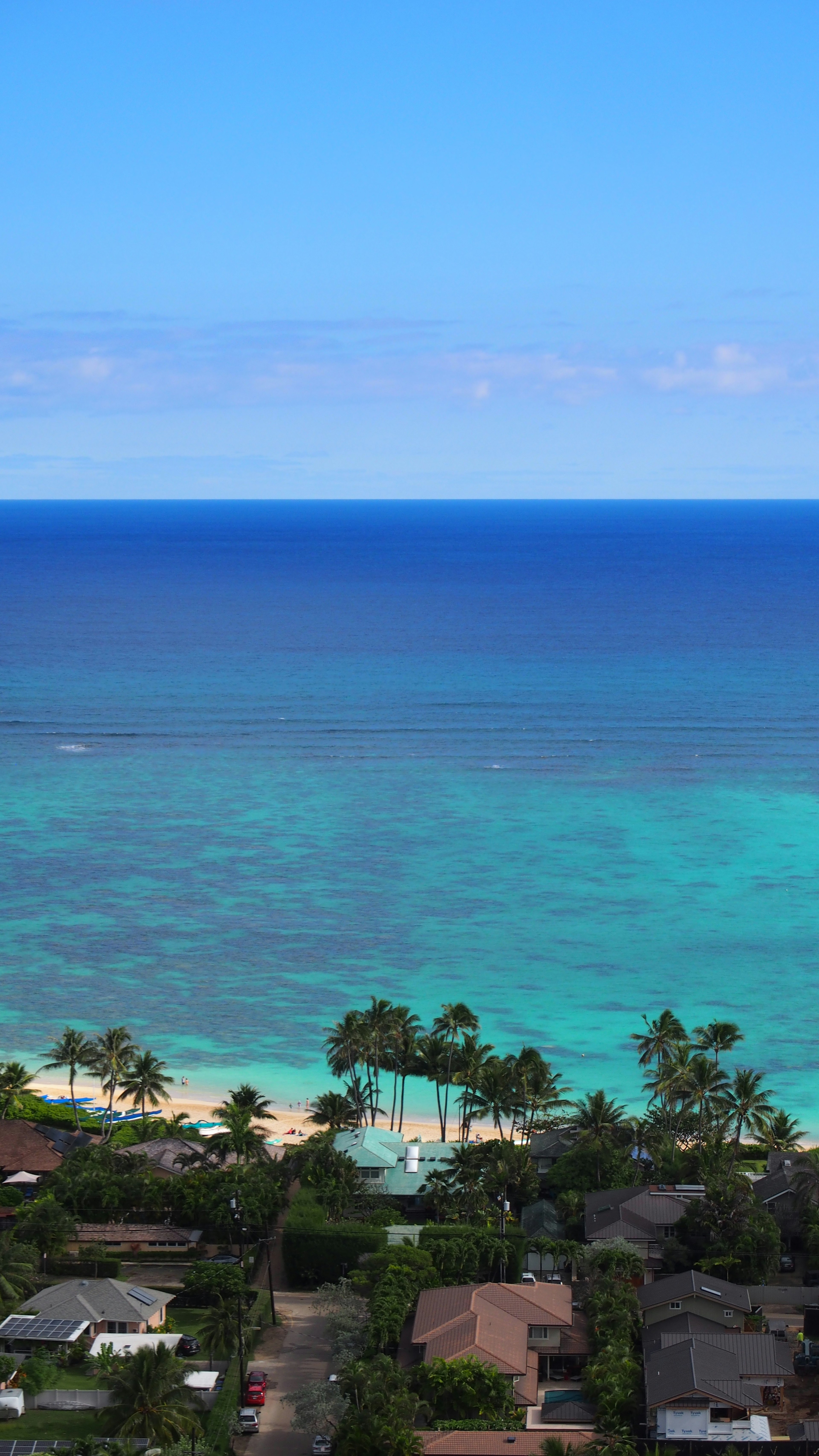 ทิวทัศน์อันงดงามของมหาสมุทรสีน้ำเงินและท้องฟ้ากับชายหาดและต้นปาล์มในพื้นหลัง