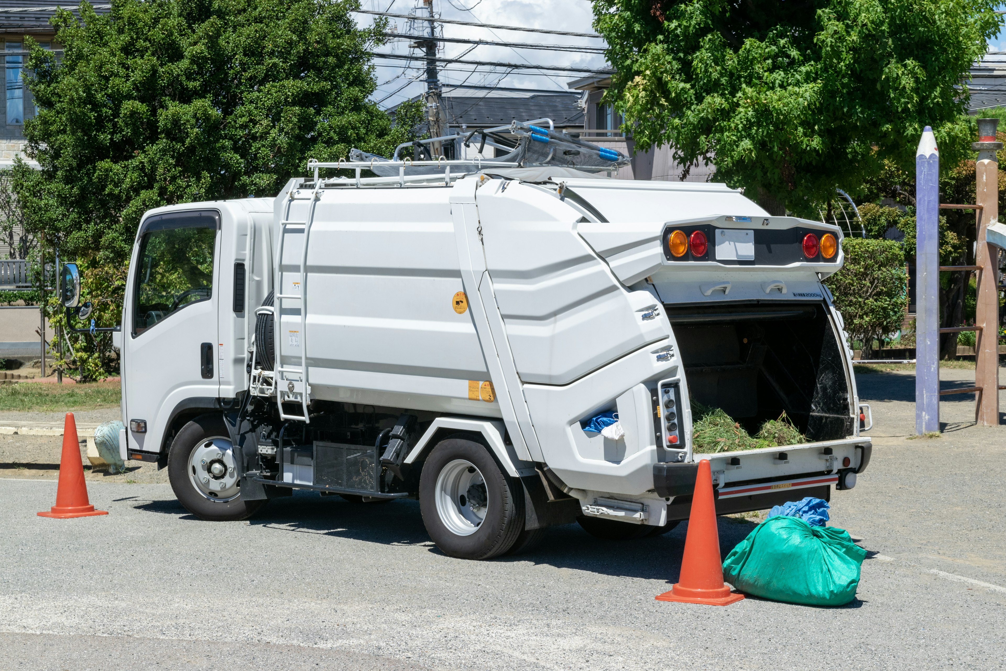 停靠在橙色锥形标志旁的白色垃圾车