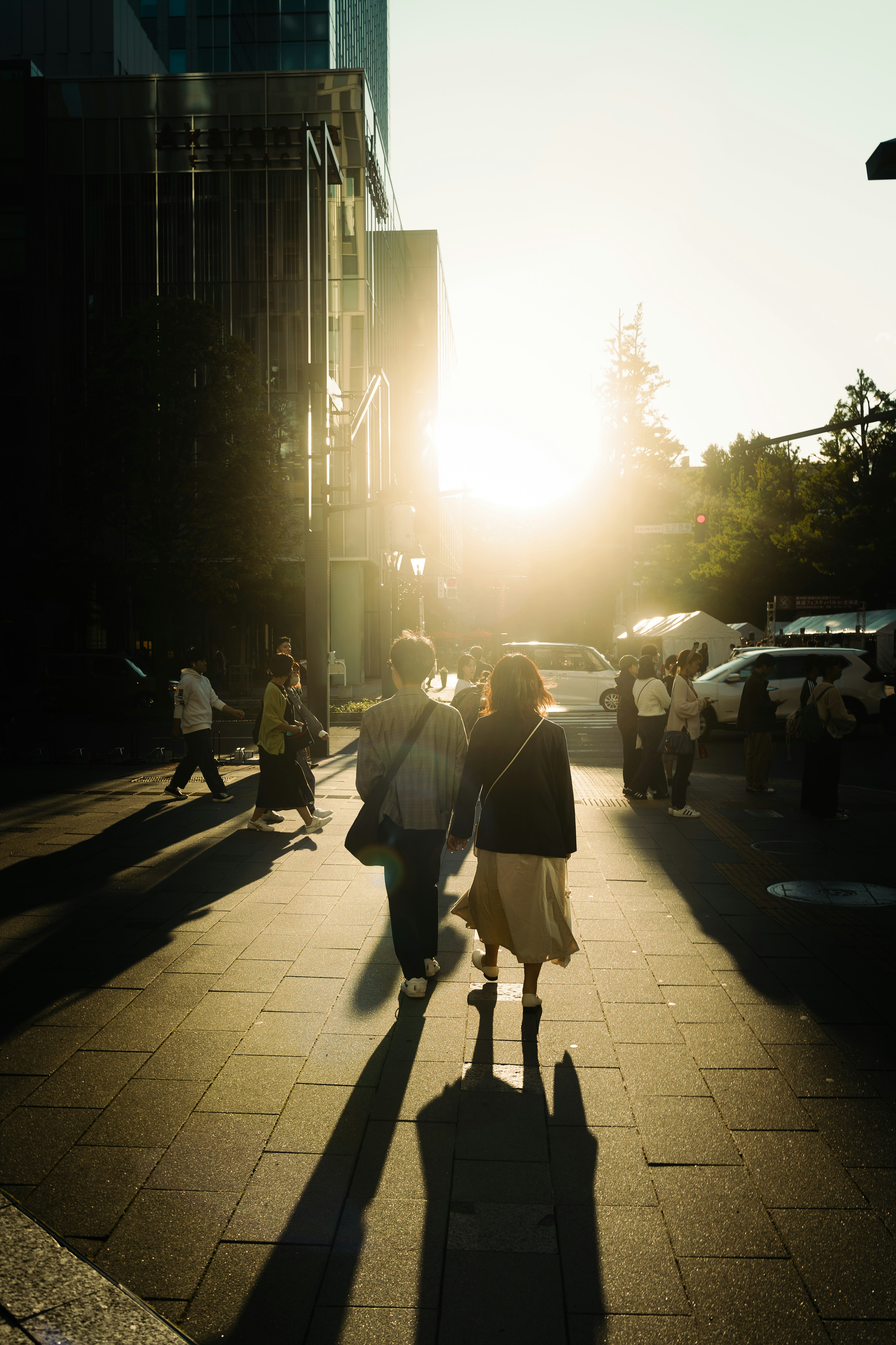 夕日を背にした街の中を歩く人々のシルエット