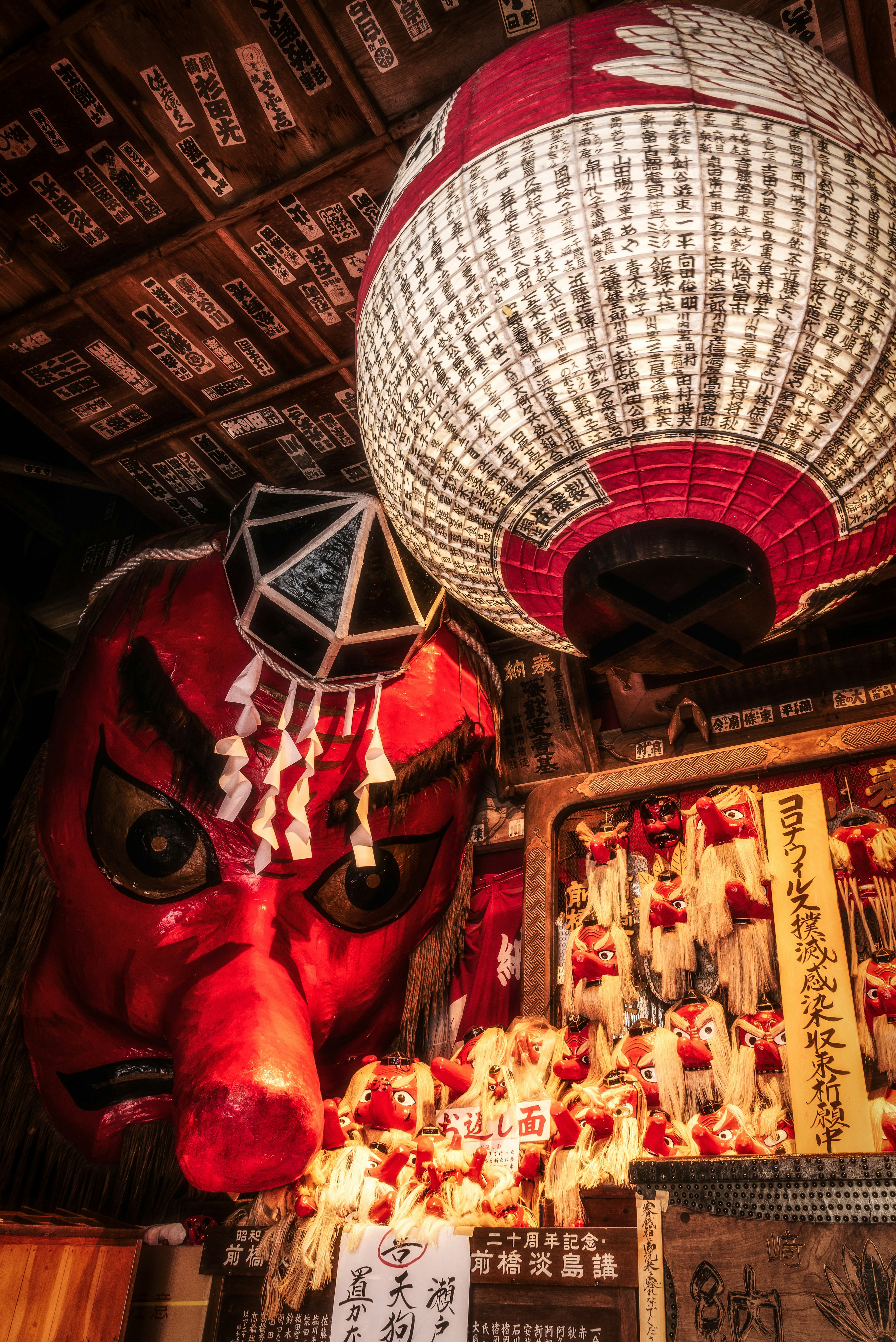 Un visage de démon rouge vif et de grandes lanternes dans un cadre culturel japonais