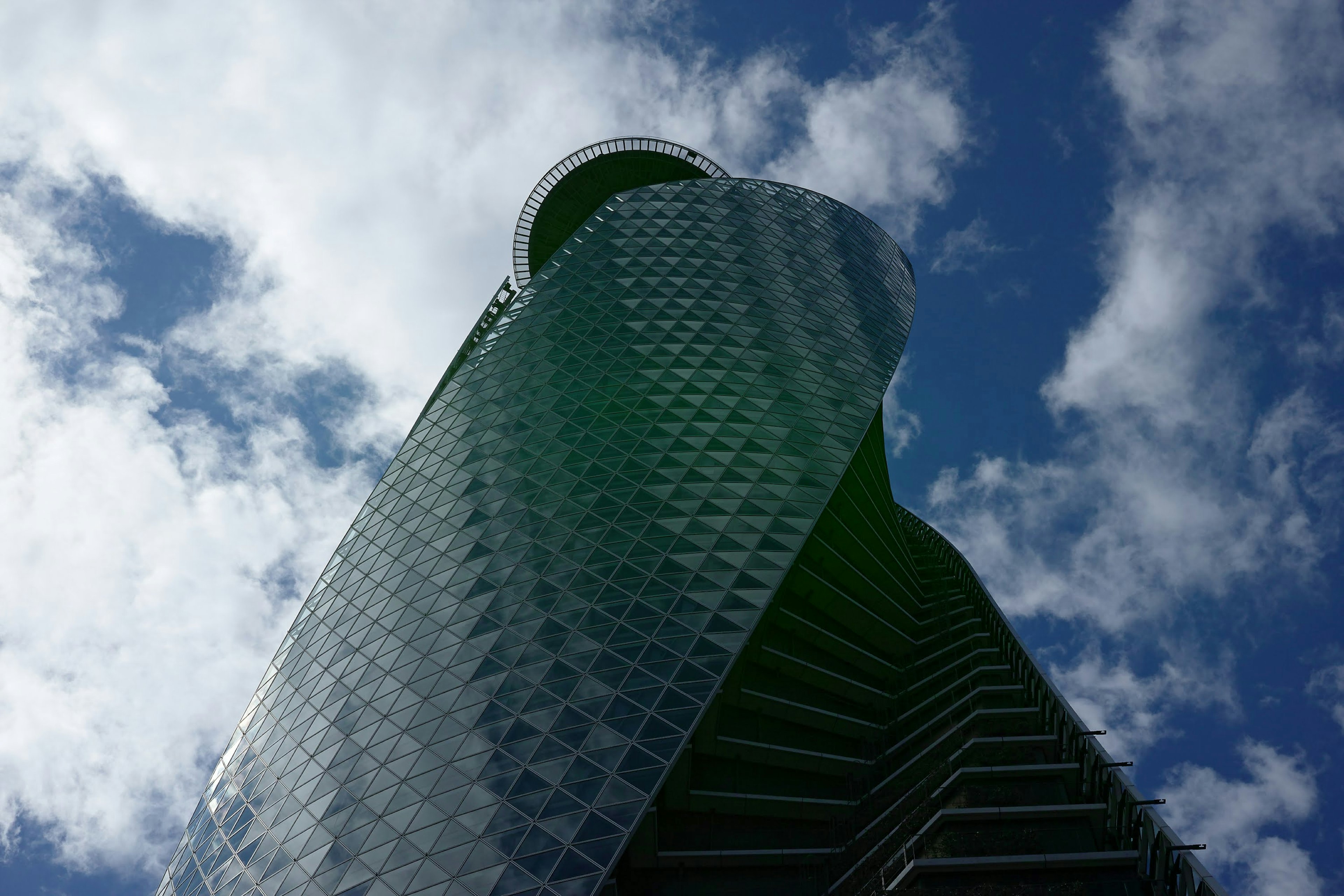 Image of a skyscraper viewed from below with blue sky and clouds