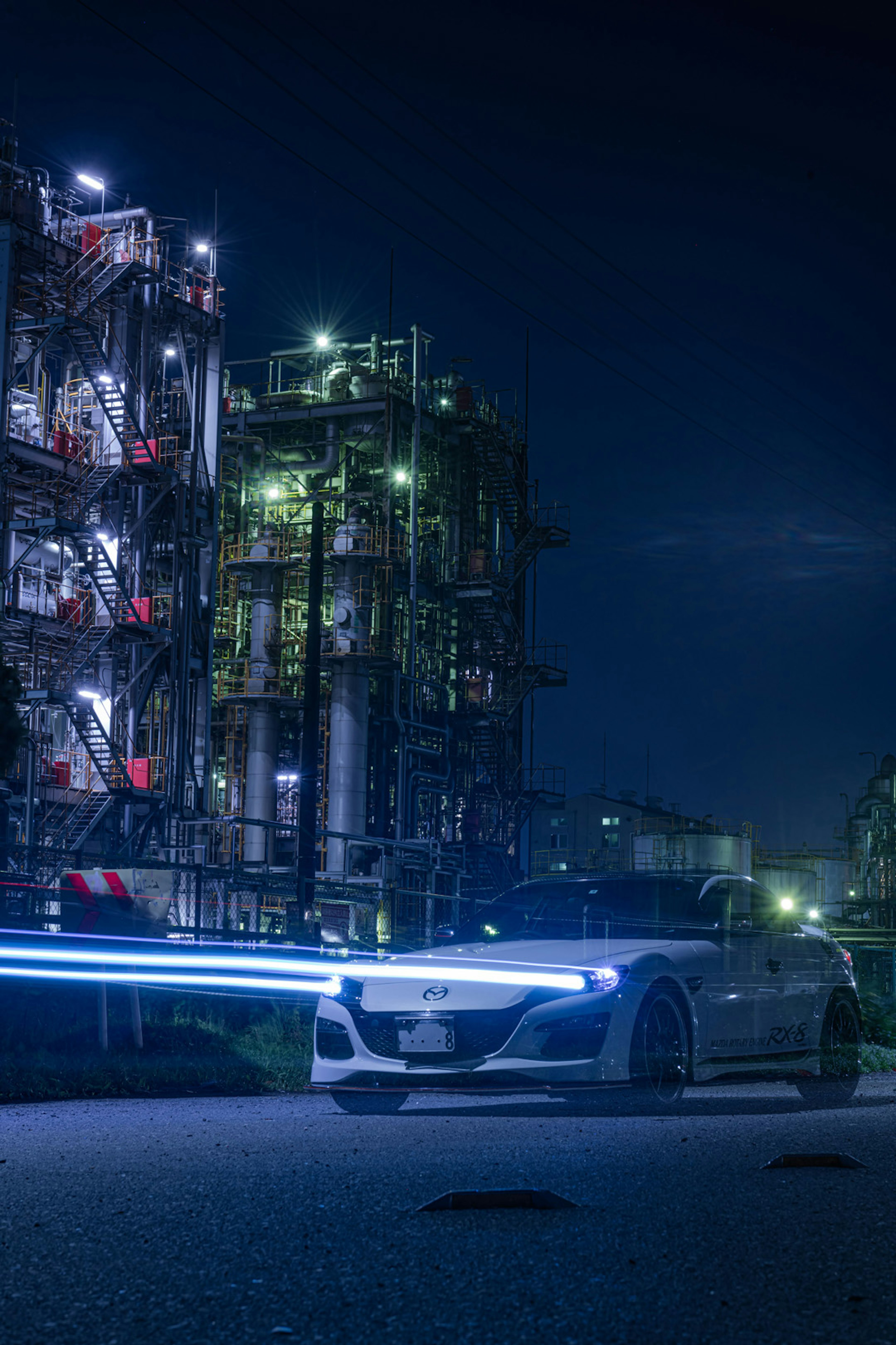 A bright car with light trails next to a construction site at night