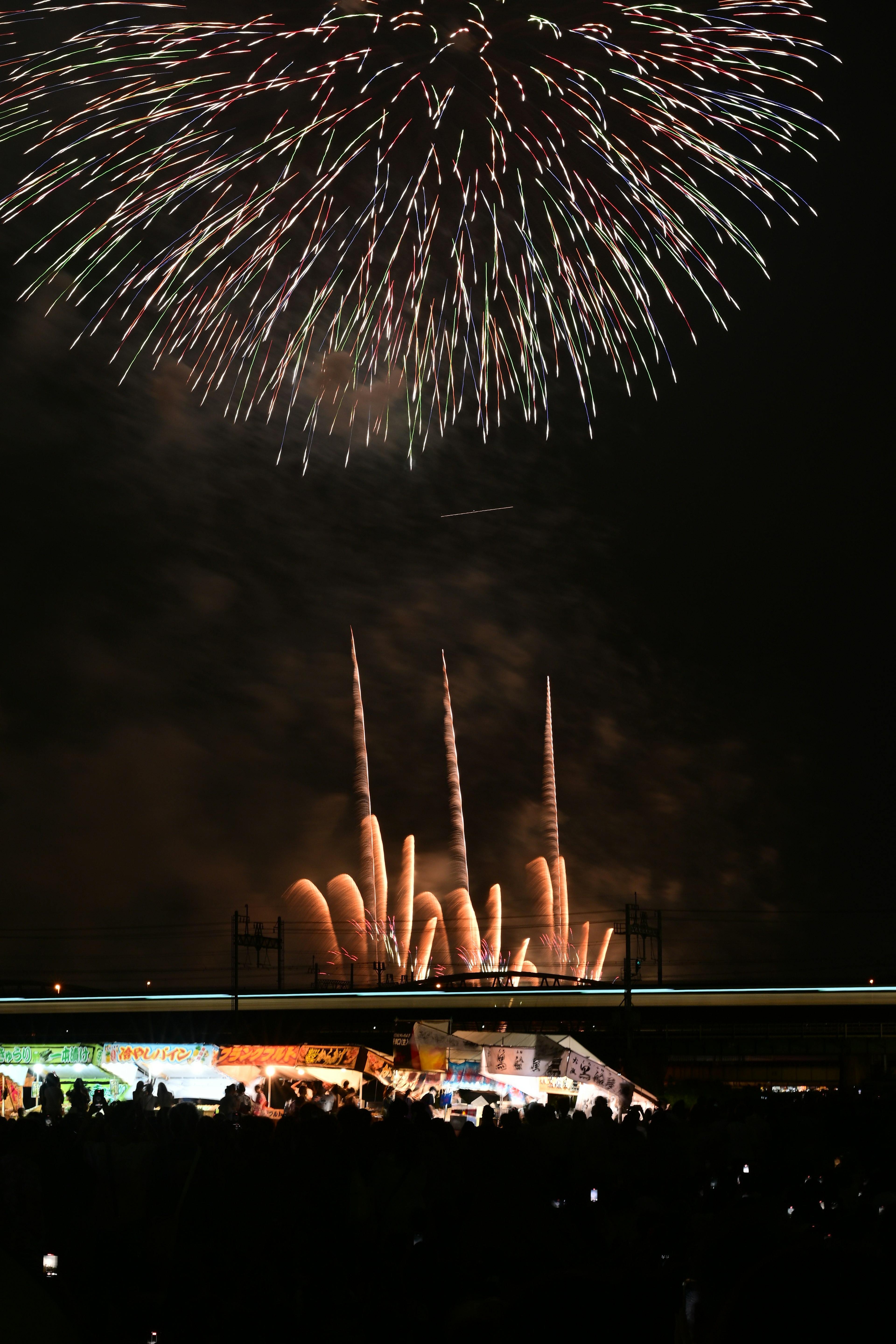 Colorful fireworks illuminating the night sky with silhouettes of spectators