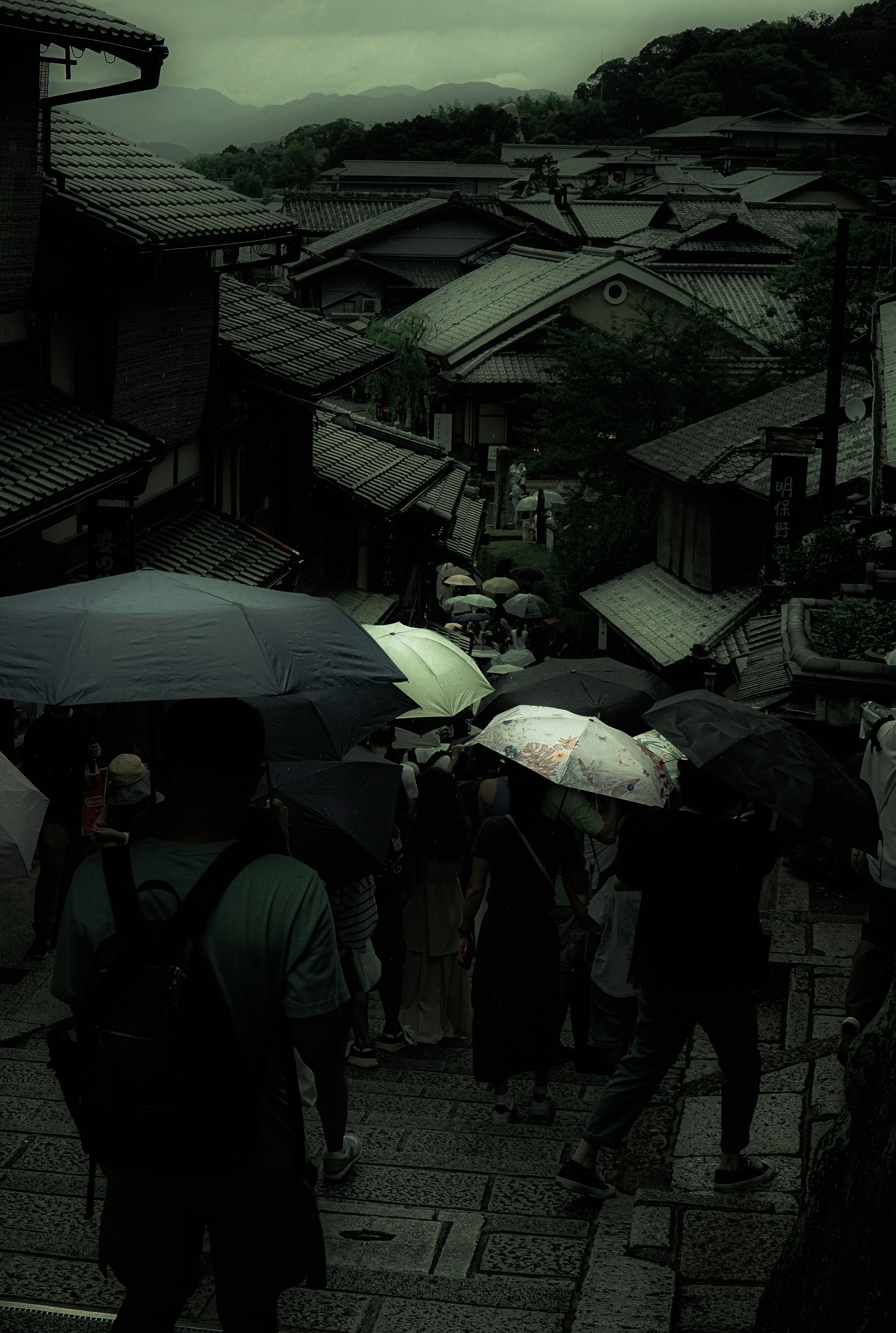 霧の中で傘を持った人々が歩いている古い街並み