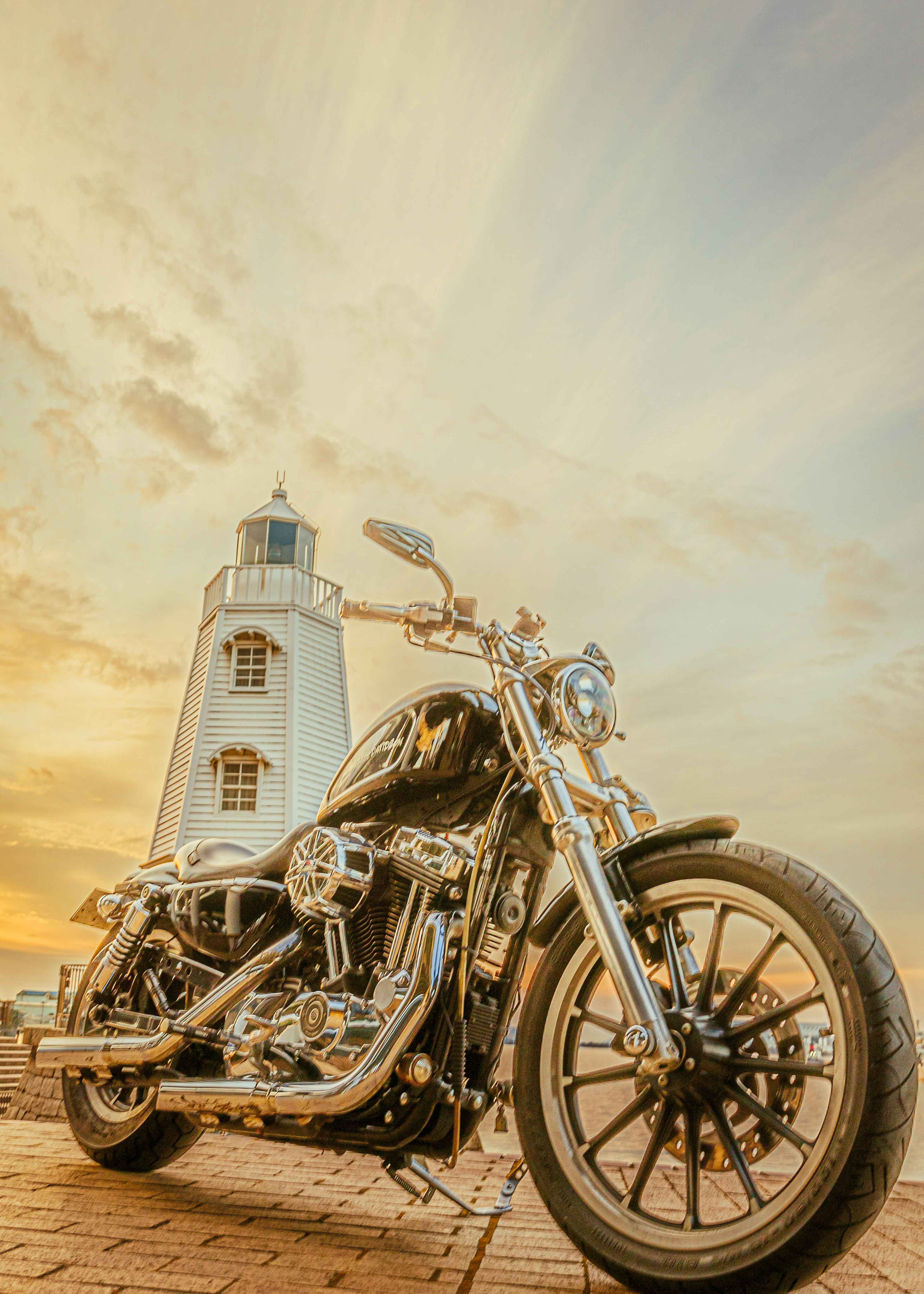 Eine Harley-Davidson-Motorrad vor einem Leuchtturm unter einem schönen Sonnenuntergangshimmel