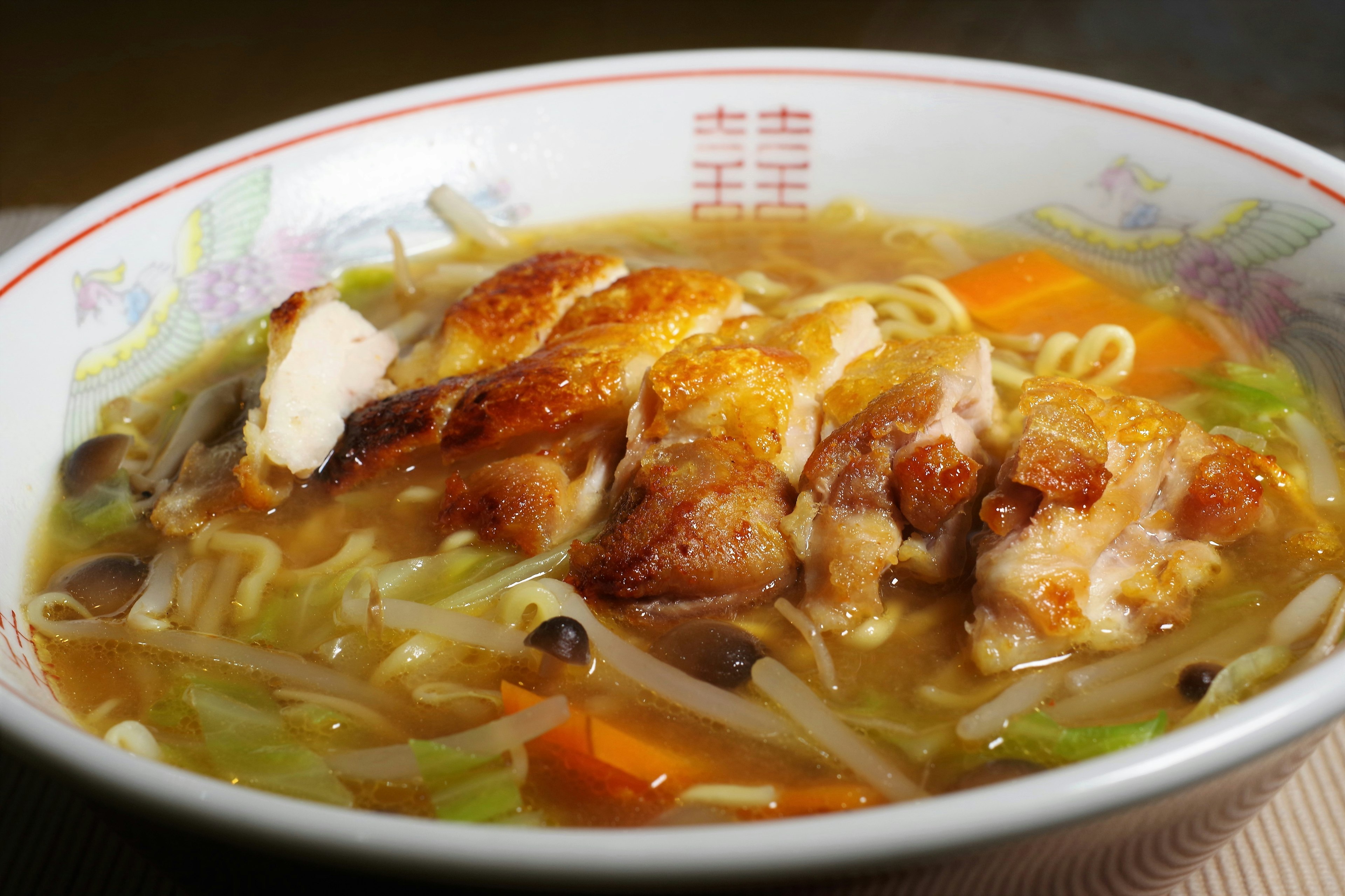 Bowl of ramen with chicken topped with vegetables and broth