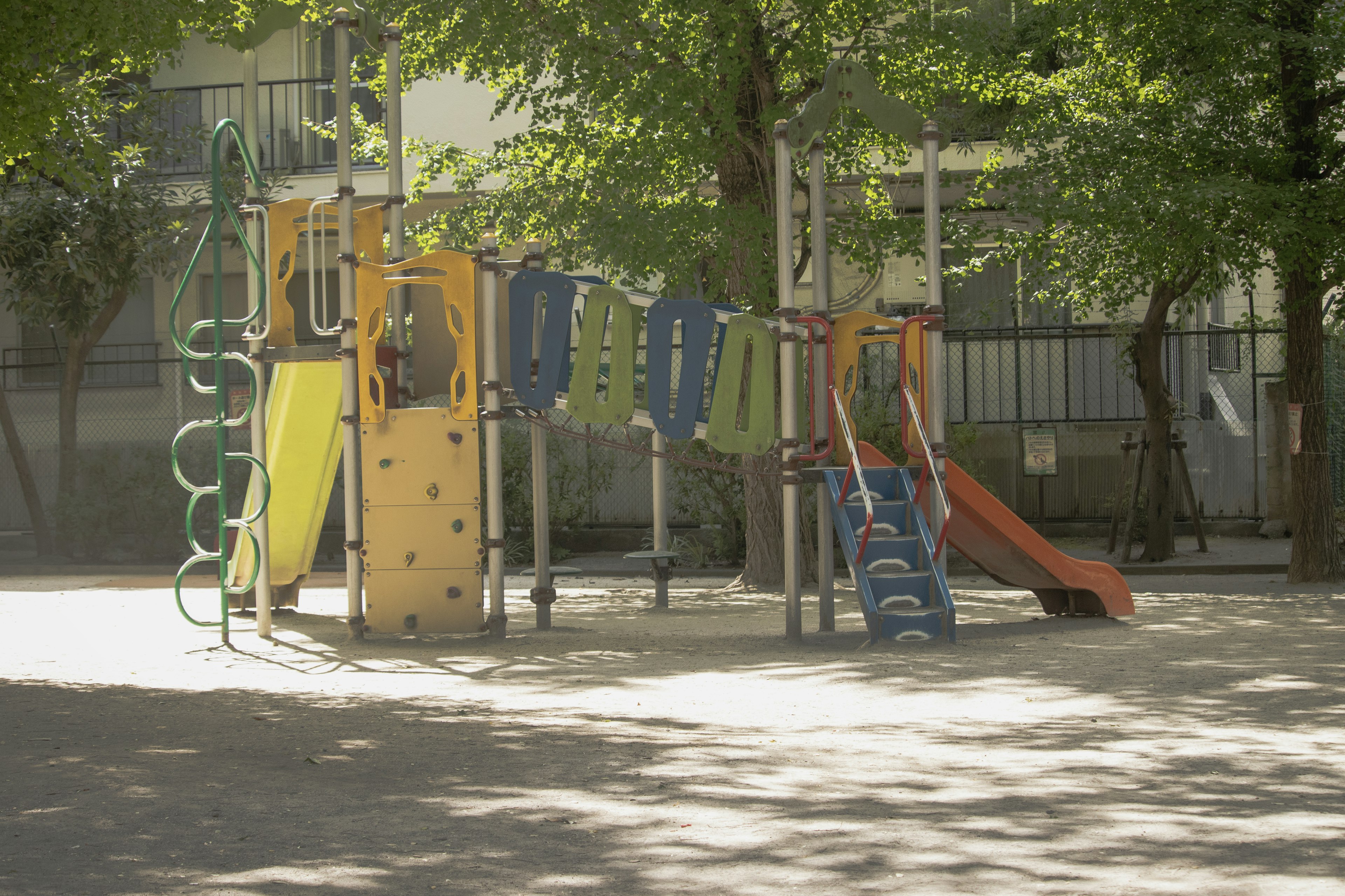 Playground equipment in a sunny park setting with slides and climbing structures