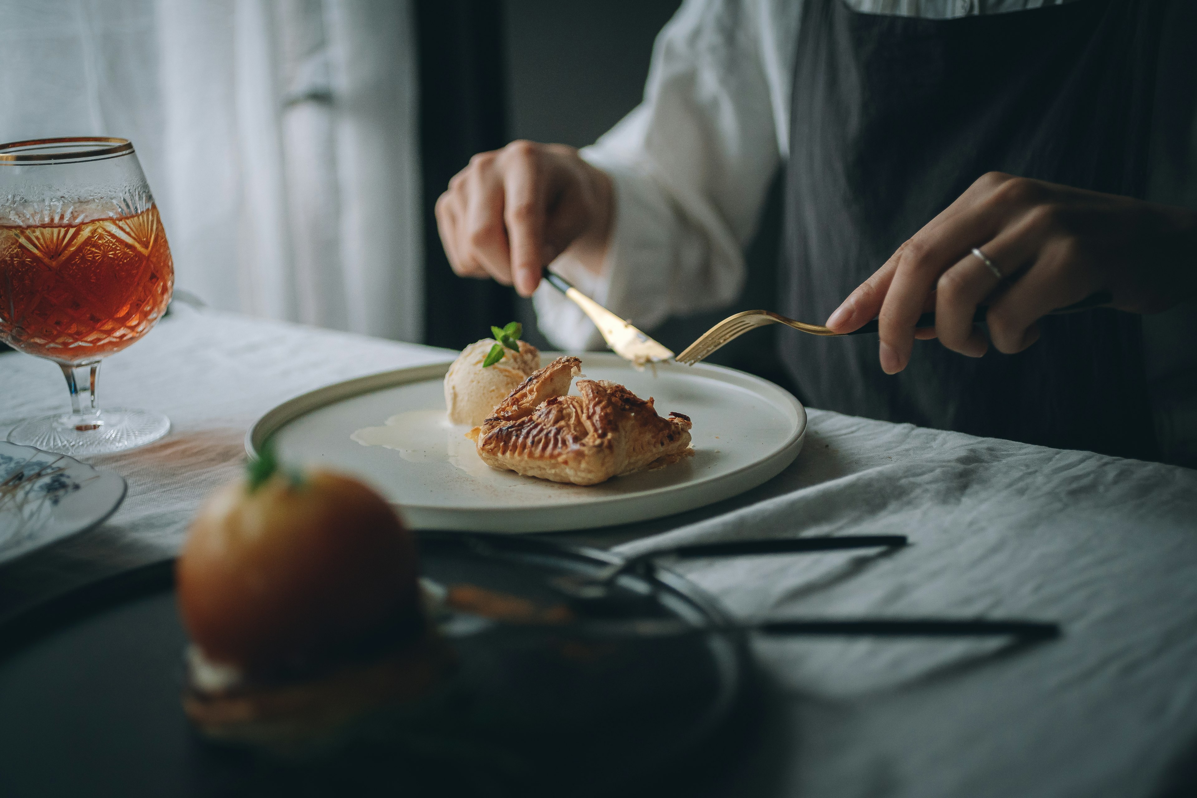 Nahaufnahme von Händen, die eine Mahlzeit mit Dessert und Getränk genießen