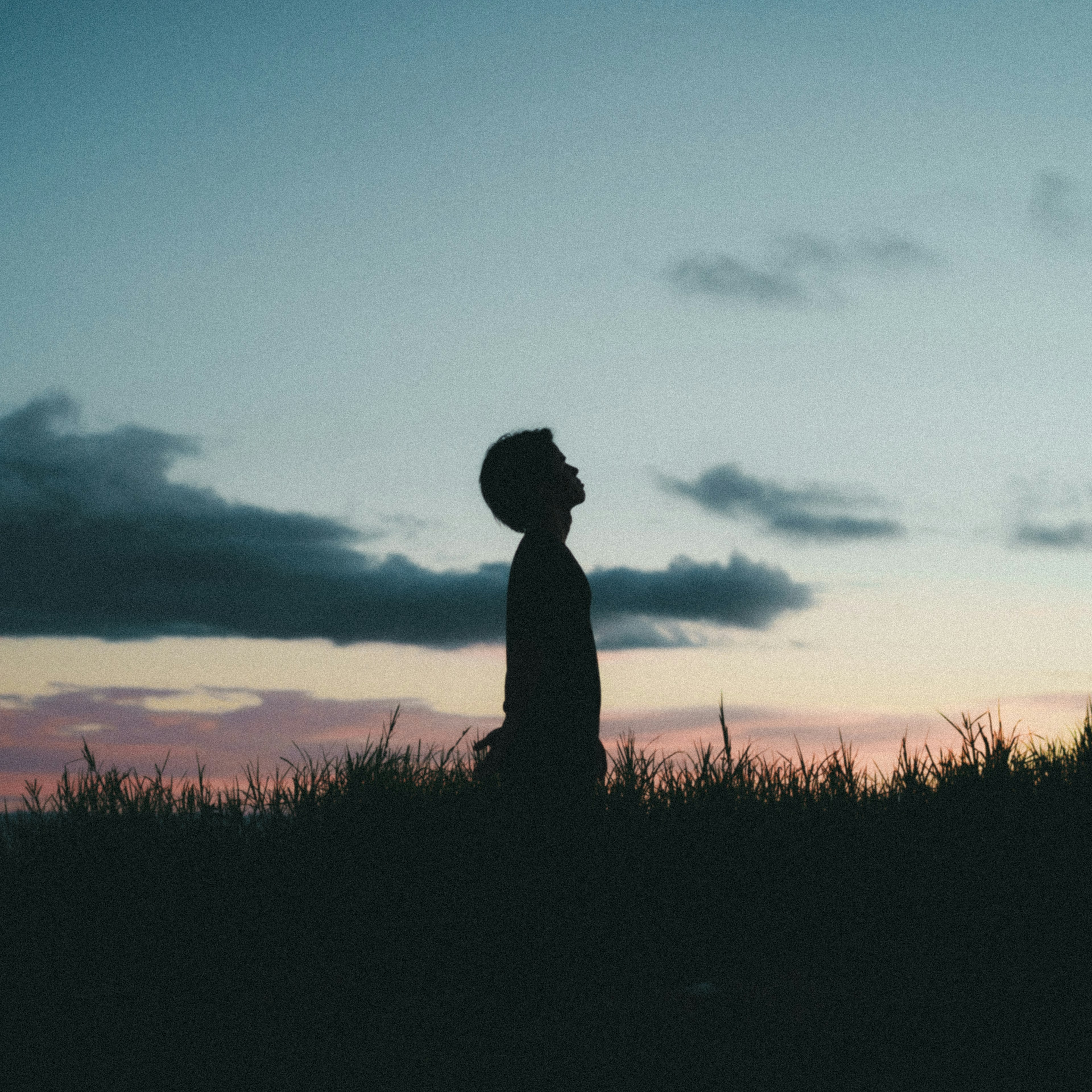 Silhouette eines Jungen, der unter einem Dämmerungshimmel steht