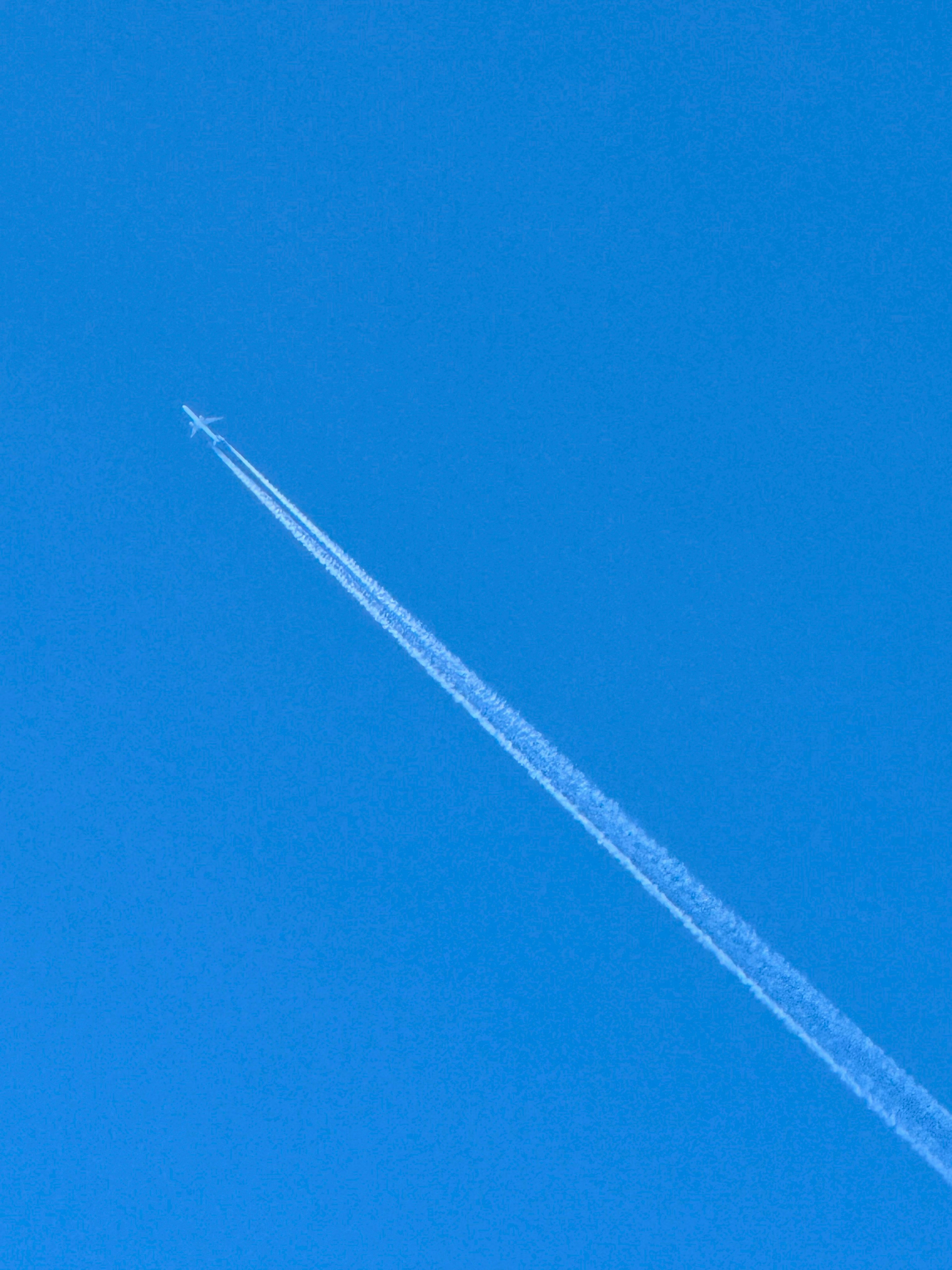 Flugzeug fliegt im blauen Himmel und hinterlässt eine Kondensstreifen