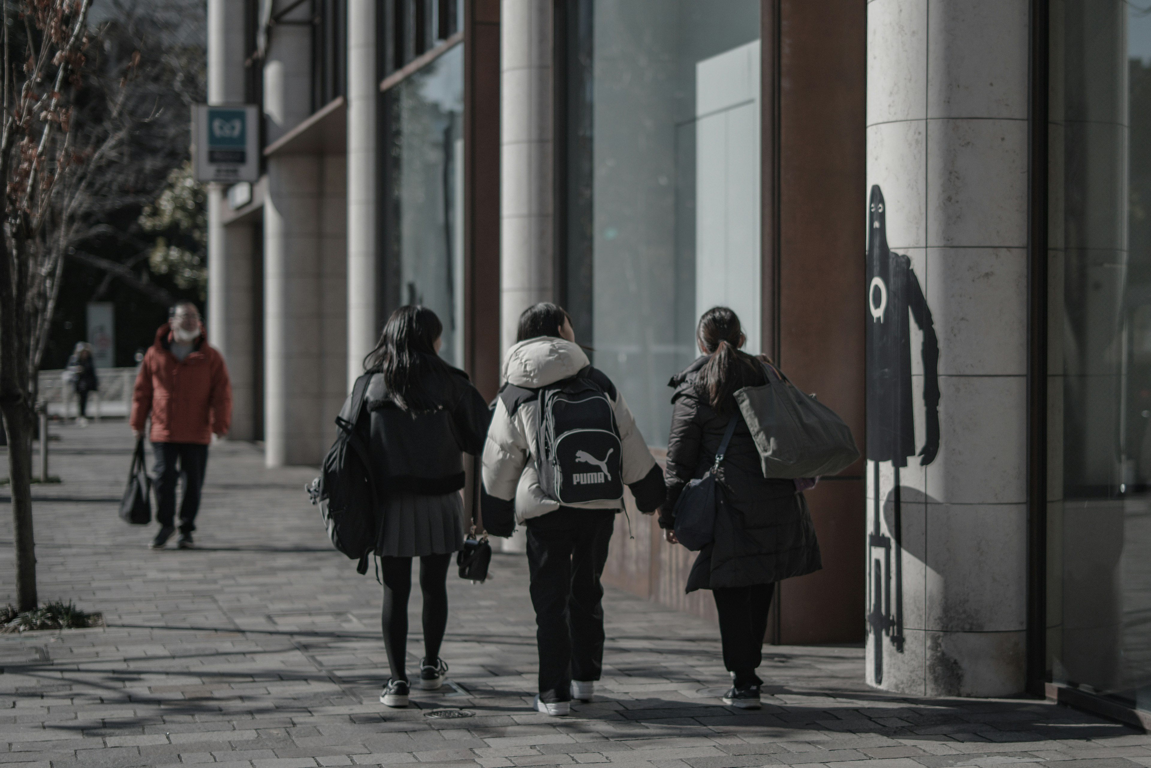 Schüler gehen die Straße entlang mit Gebäude-Fassade