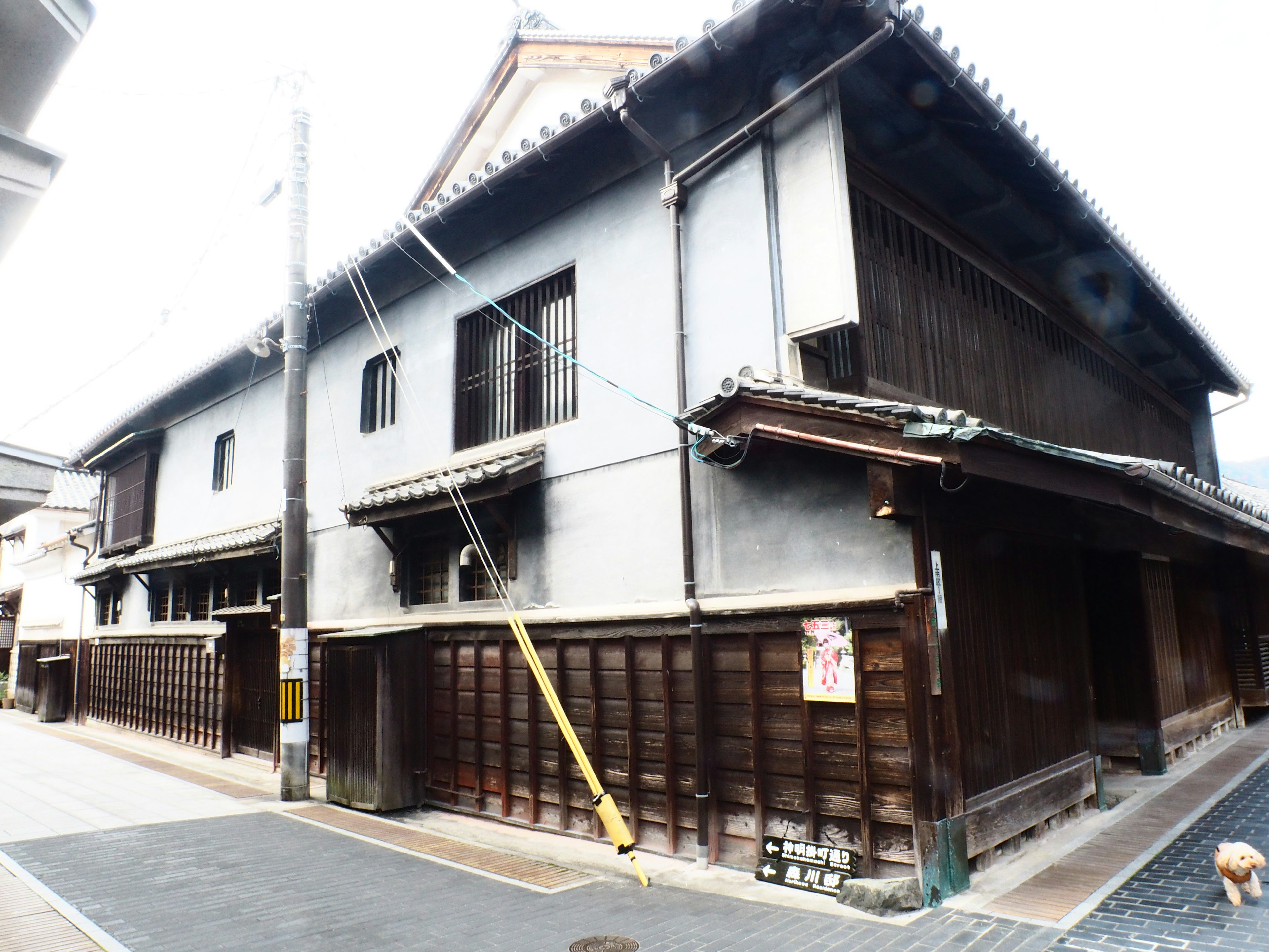 Extérieur d'un bâtiment japonais traditionnel avec des murs et un toit en bois donnant sur la rue