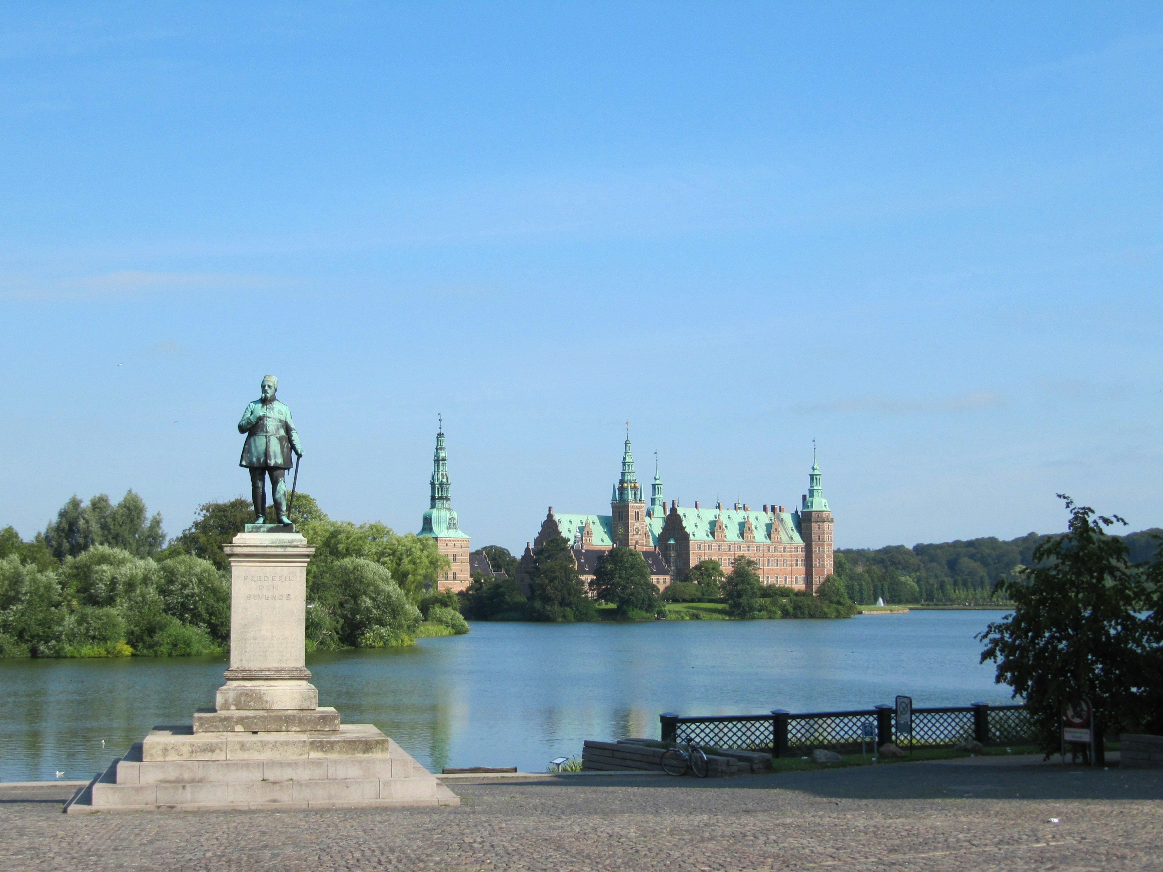 Statue in foreground with a castle in the background under a clear blue sky