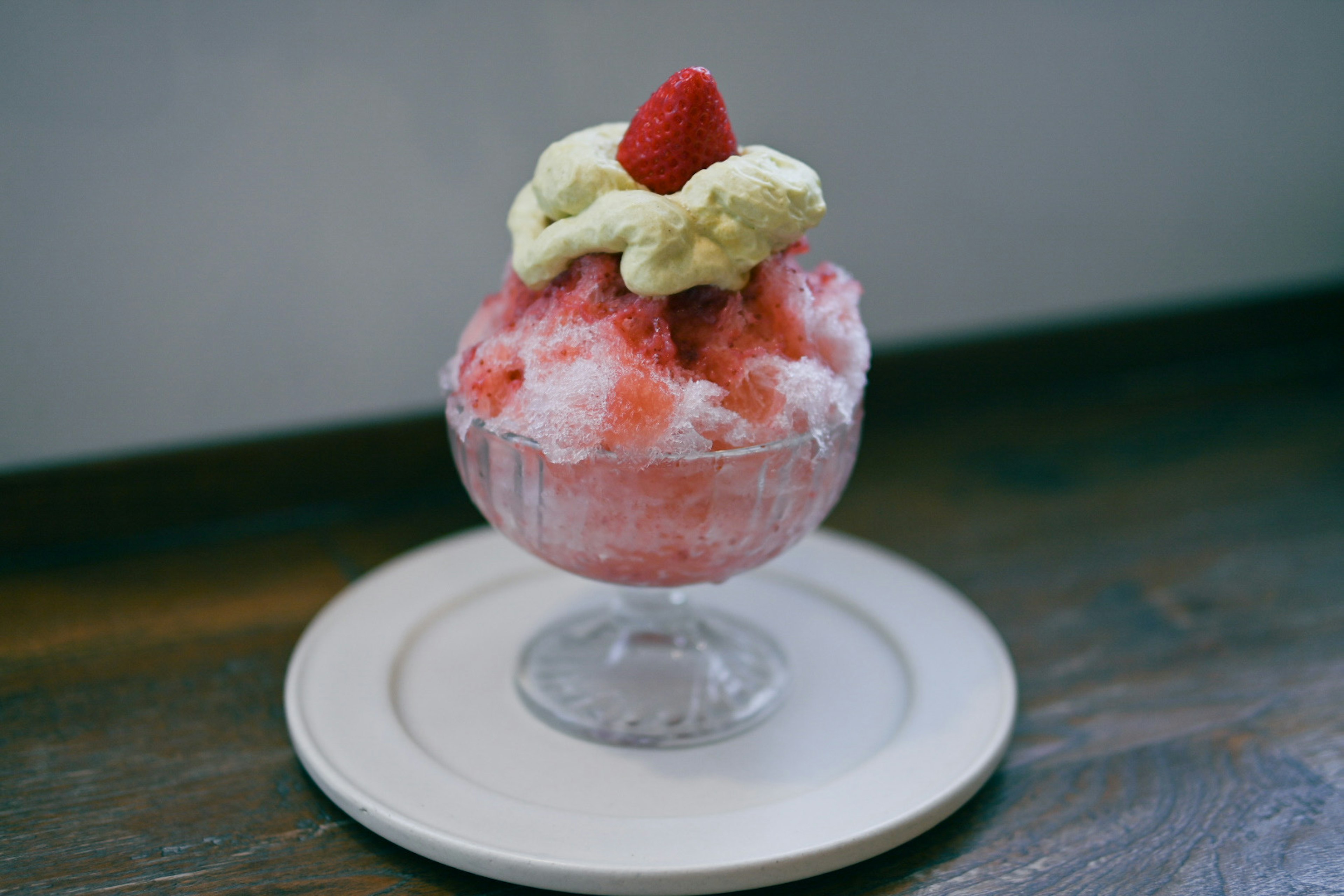 Shaved ice dessert topped with cream and a strawberry