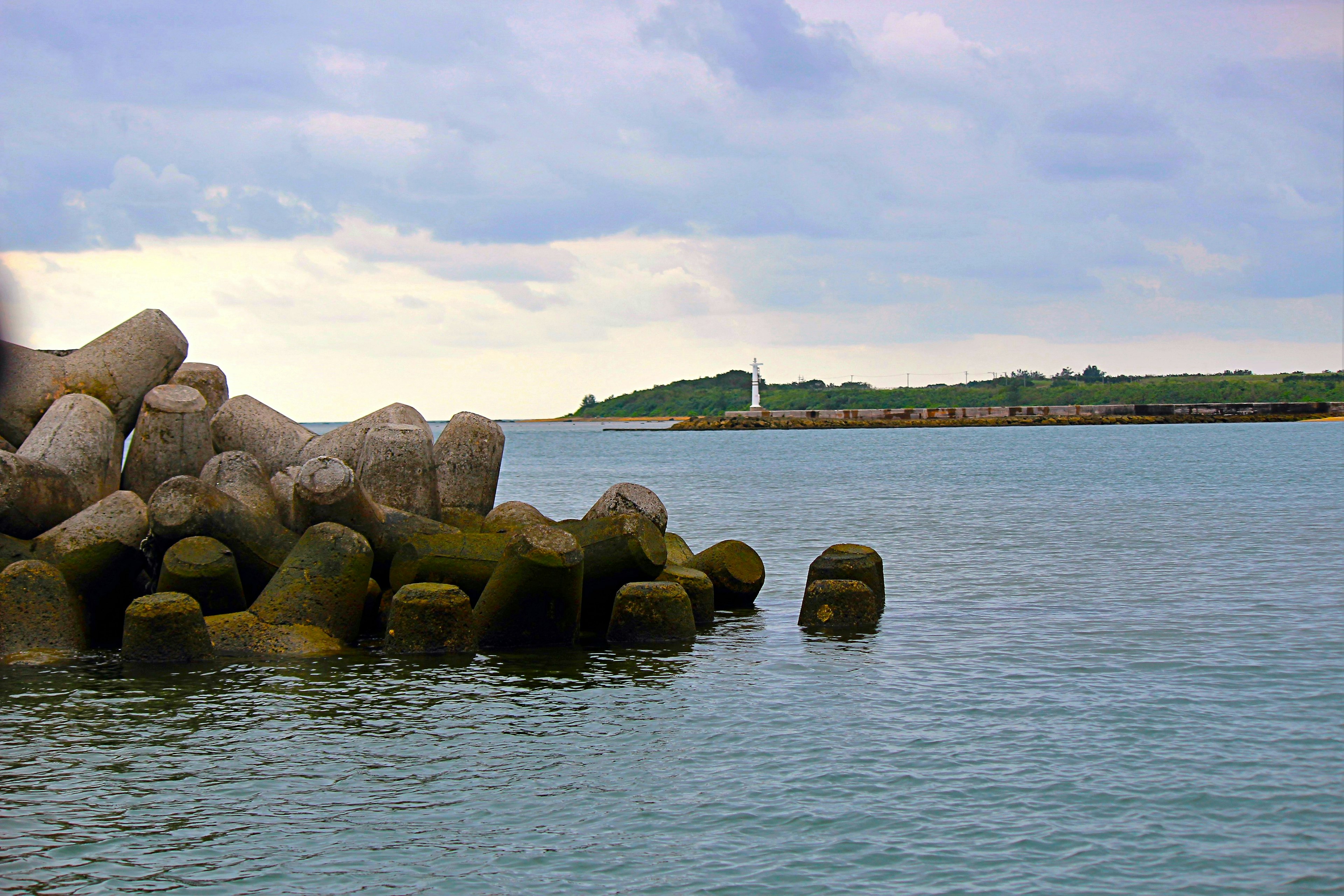 Vista de rocas costeras y faro Agua tranquila reflejando nubes