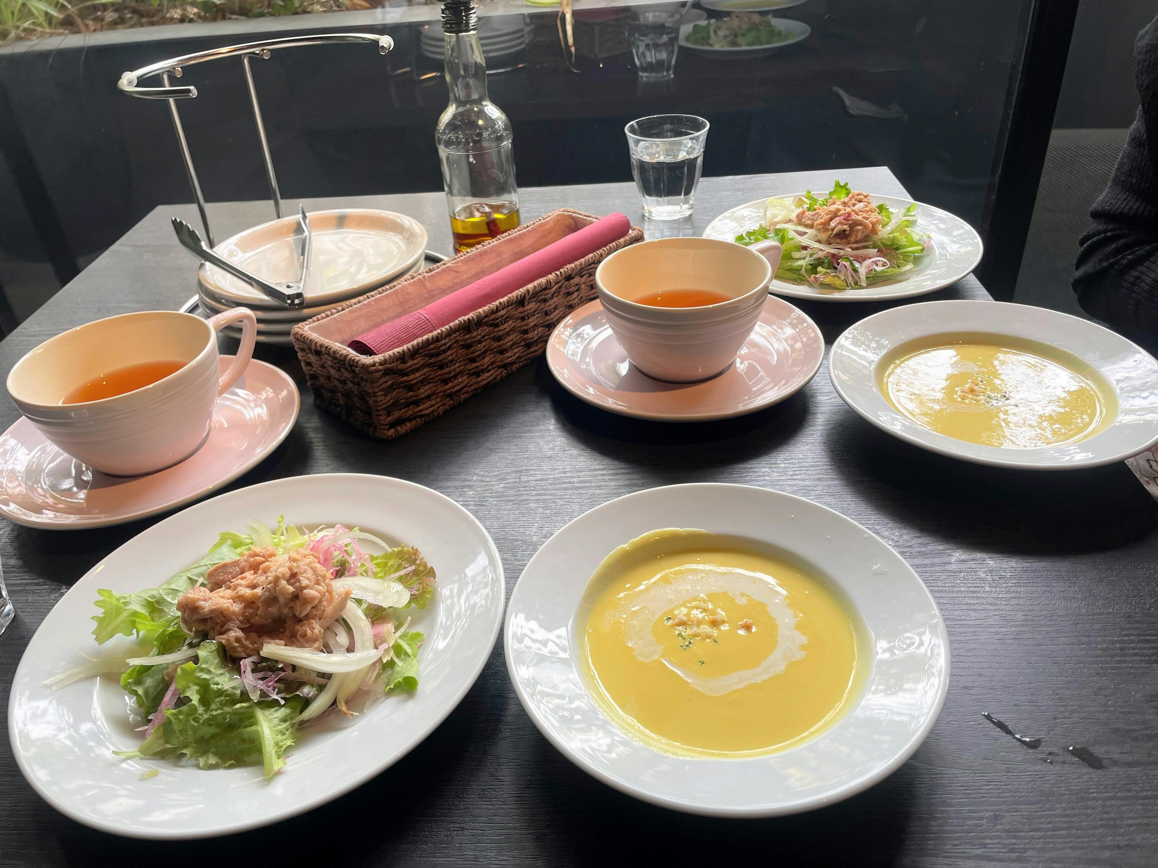 A dining scene with plates of salad and soup on the table