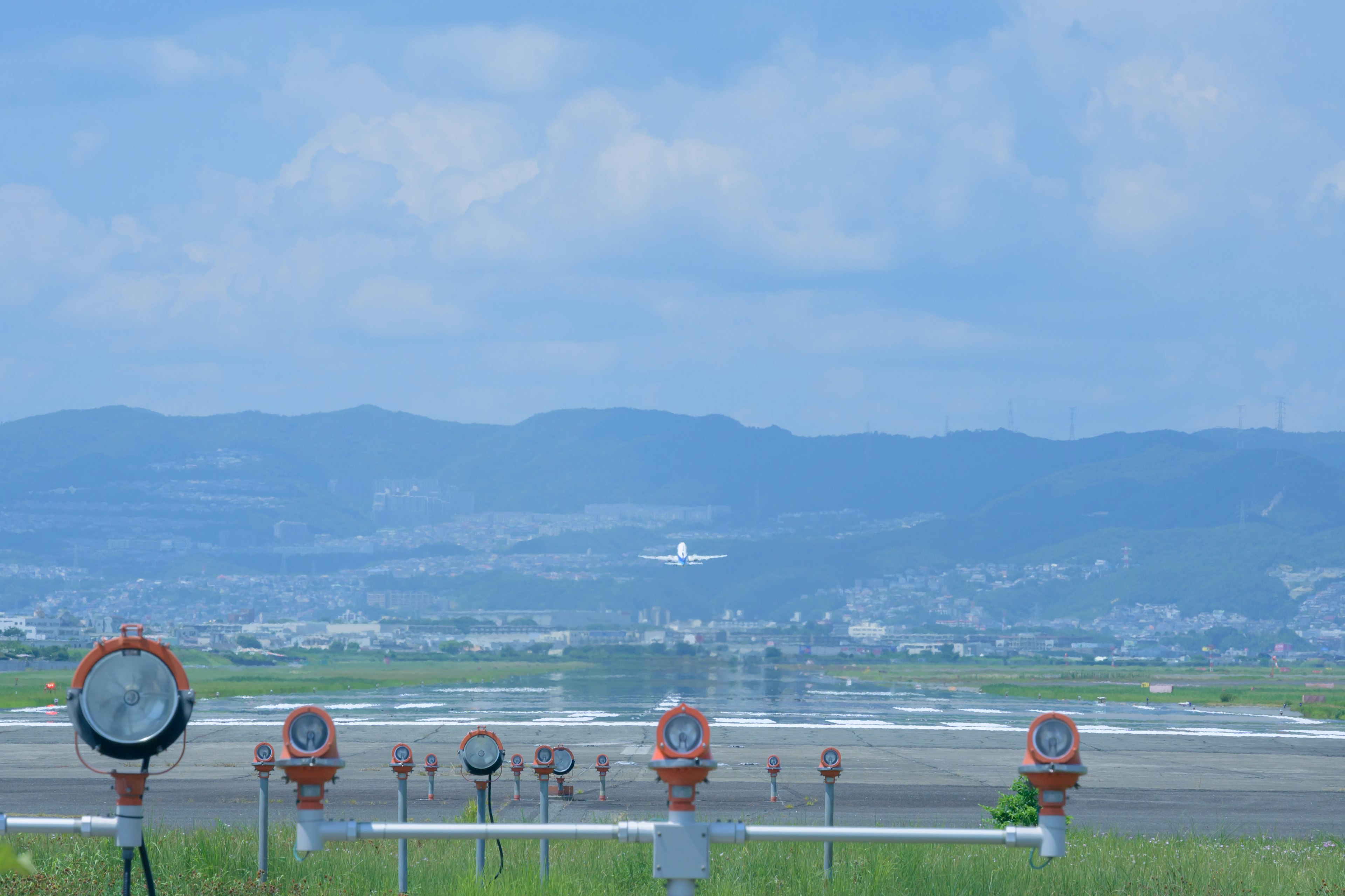 Un avión aterrizando en una pista con colinas circundantes y luces de aeropuerto