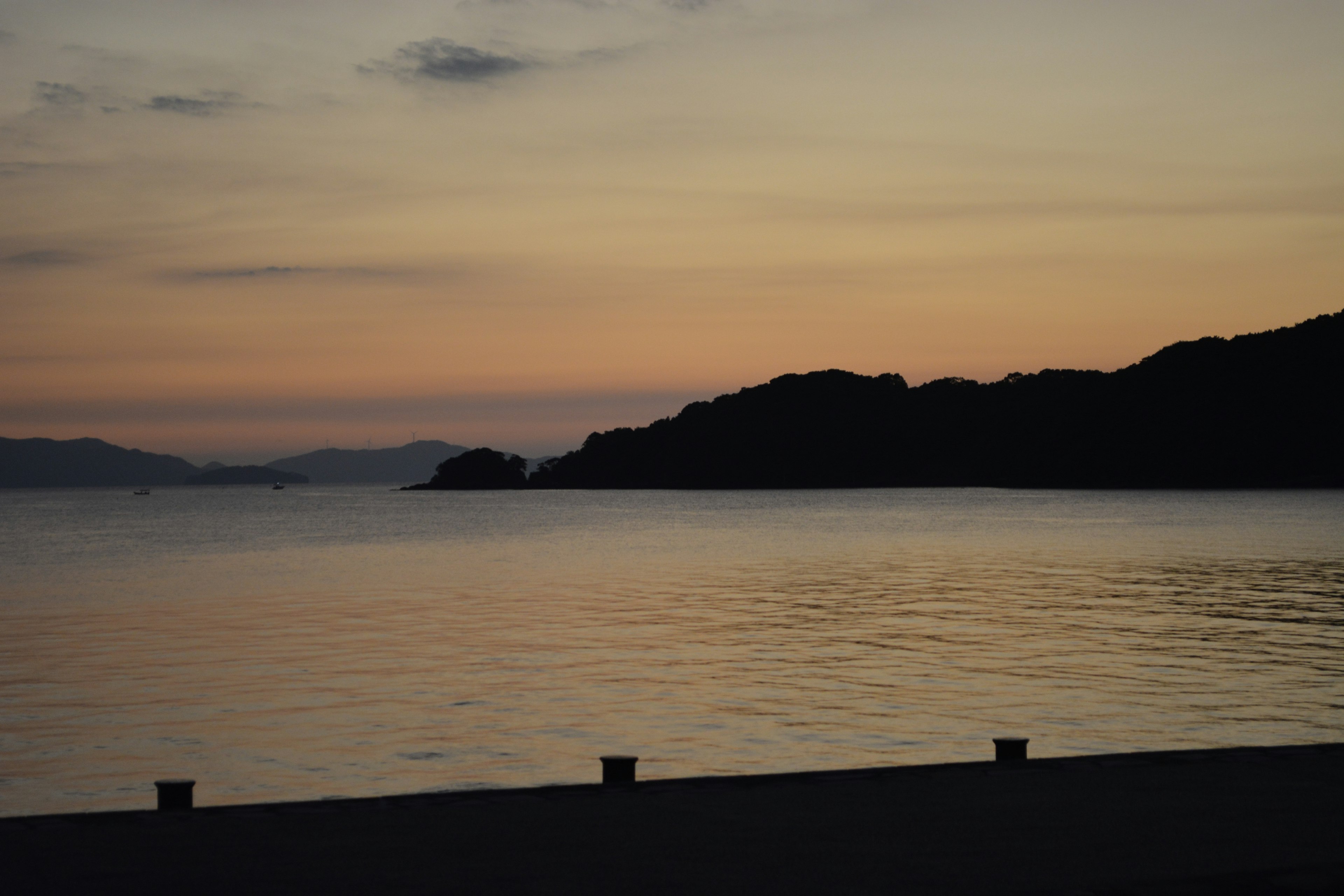 Silhouette of islands against a sunset sky over calm waters