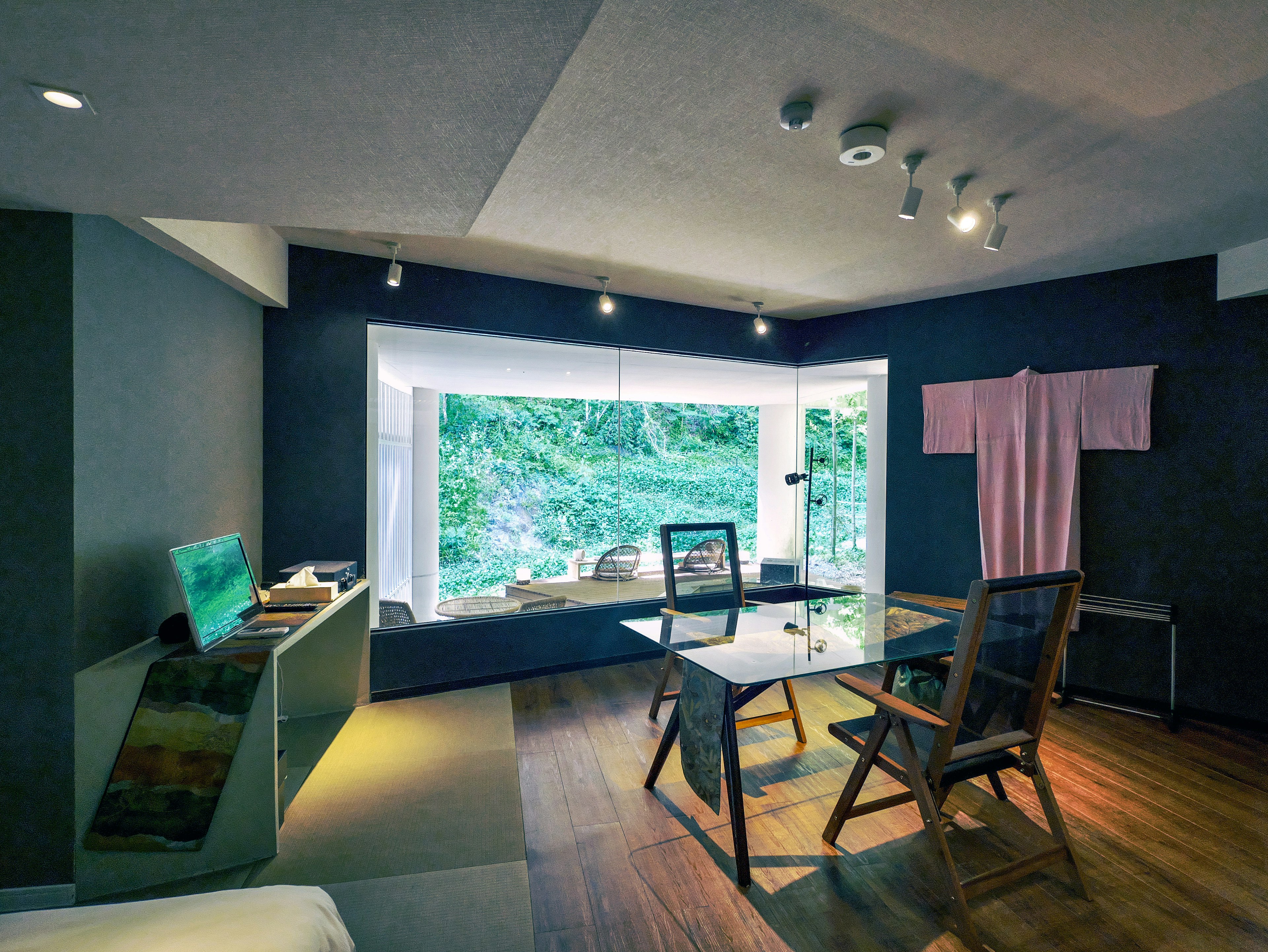 Intérieur de salon moderne avec grande fenêtre lumière naturelle et vue sur la verdure sol en bois et mobilier simple