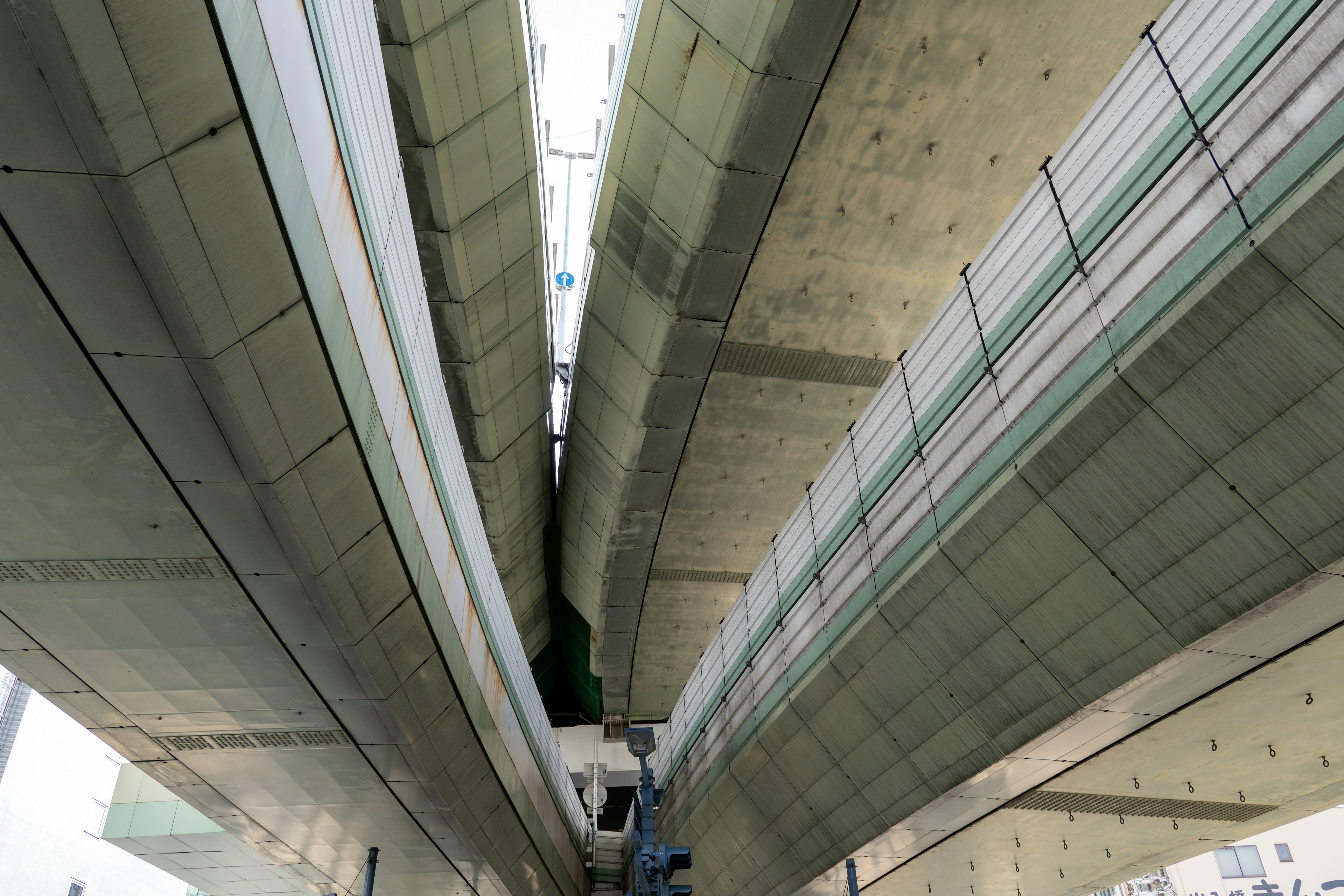 Vista desde debajo de un viaducto de concreto que muestra un diseño arquitectónico lineal