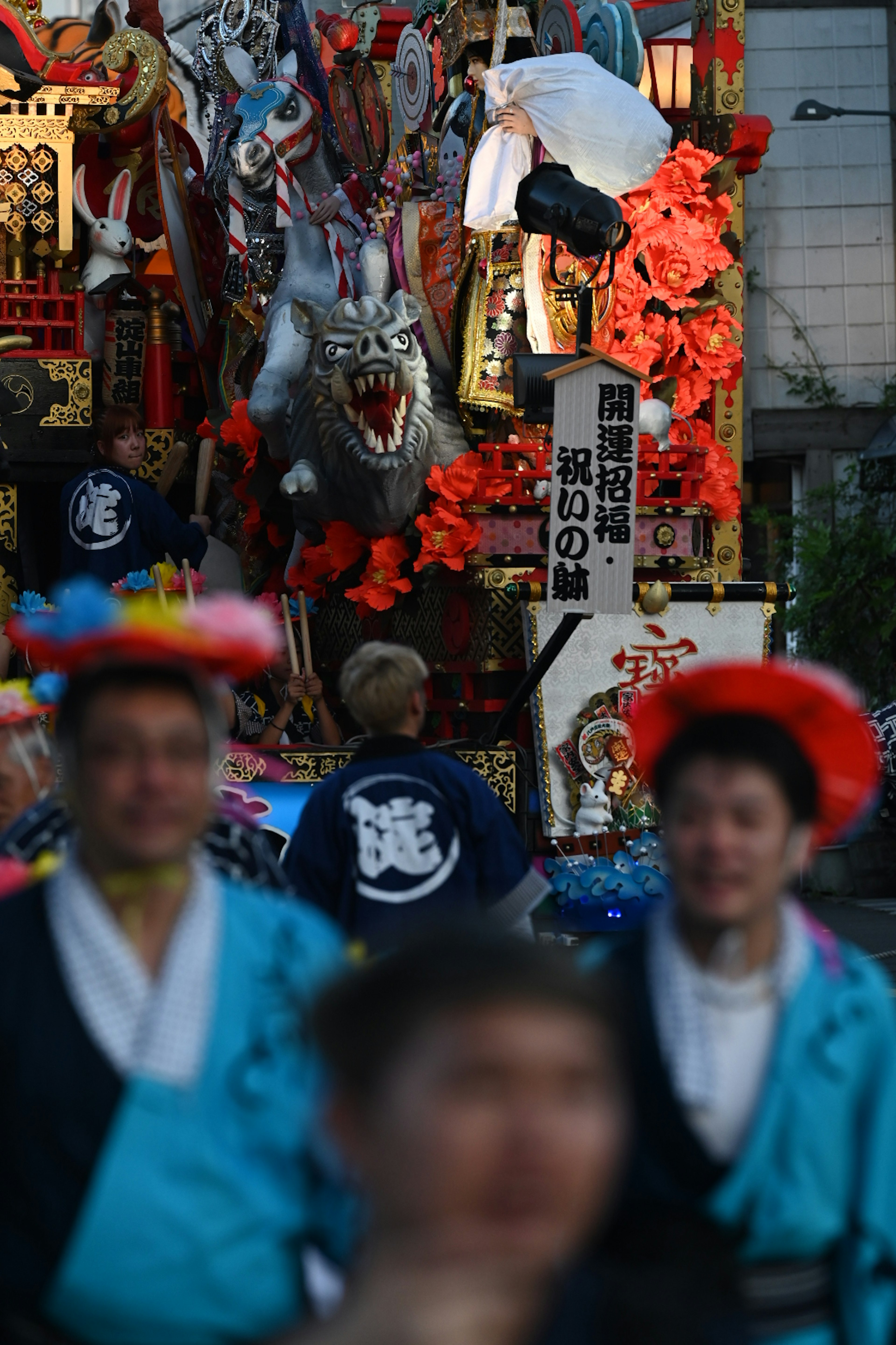 People gathered in front of festival decorations featuring a dragon and colorful flowers